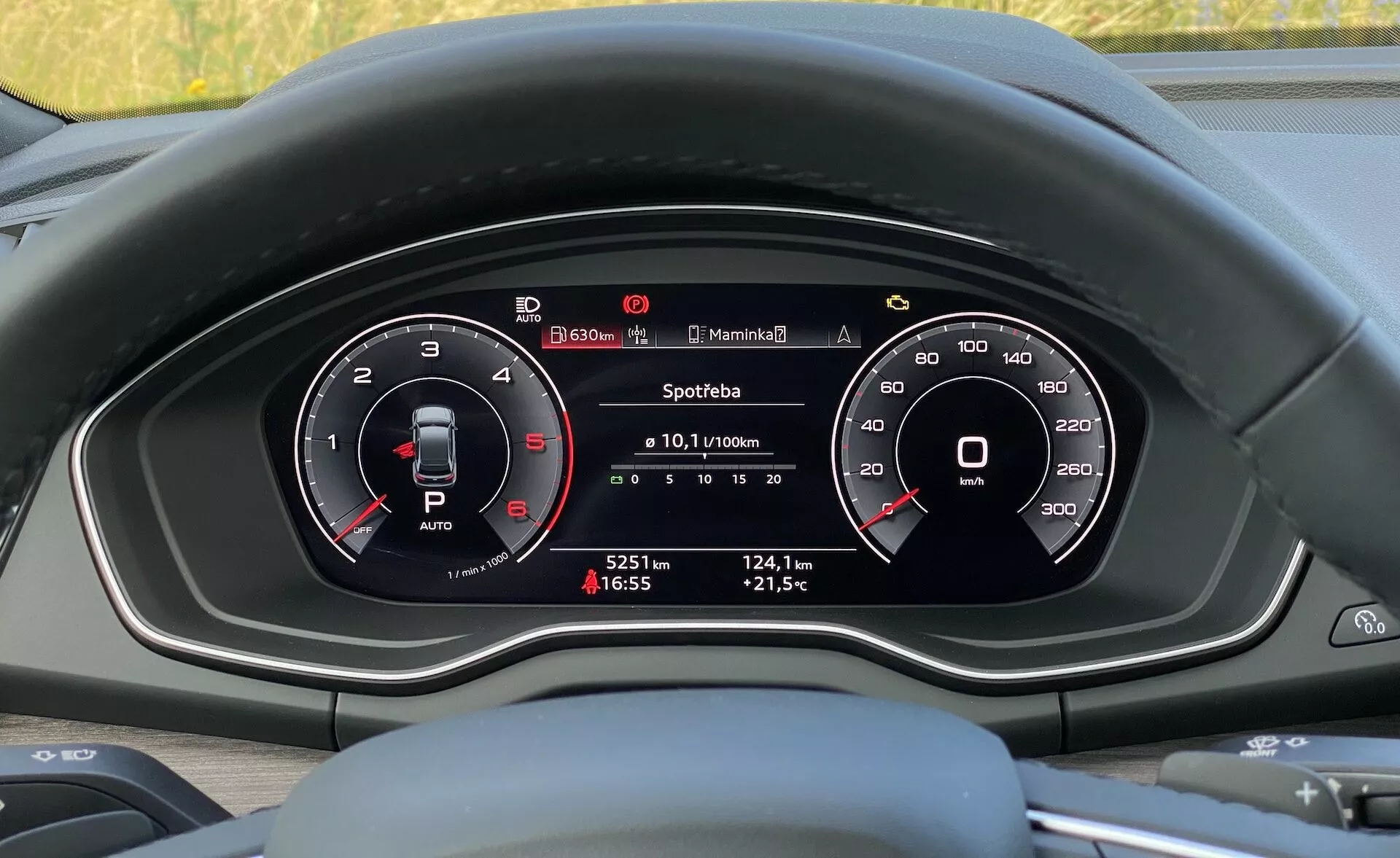 Pohľad do interiéru vozidla Audi Q5 Sportback 2020, zameraný na prístrojový panel za volantom z pohľadu vodiča, zobrazujúci zmiešaný analógový a digitálny prístrojový panel s dvoma hlavnými kruhovými meračmi (otáčkomer a rýchlomer) a centrálnym digitálnym displejom, ktorý zobrazuje informácie o vozidle, ako je spotreba paliva, prejdená vzdialenosť, vonkajšia teplota a čas.