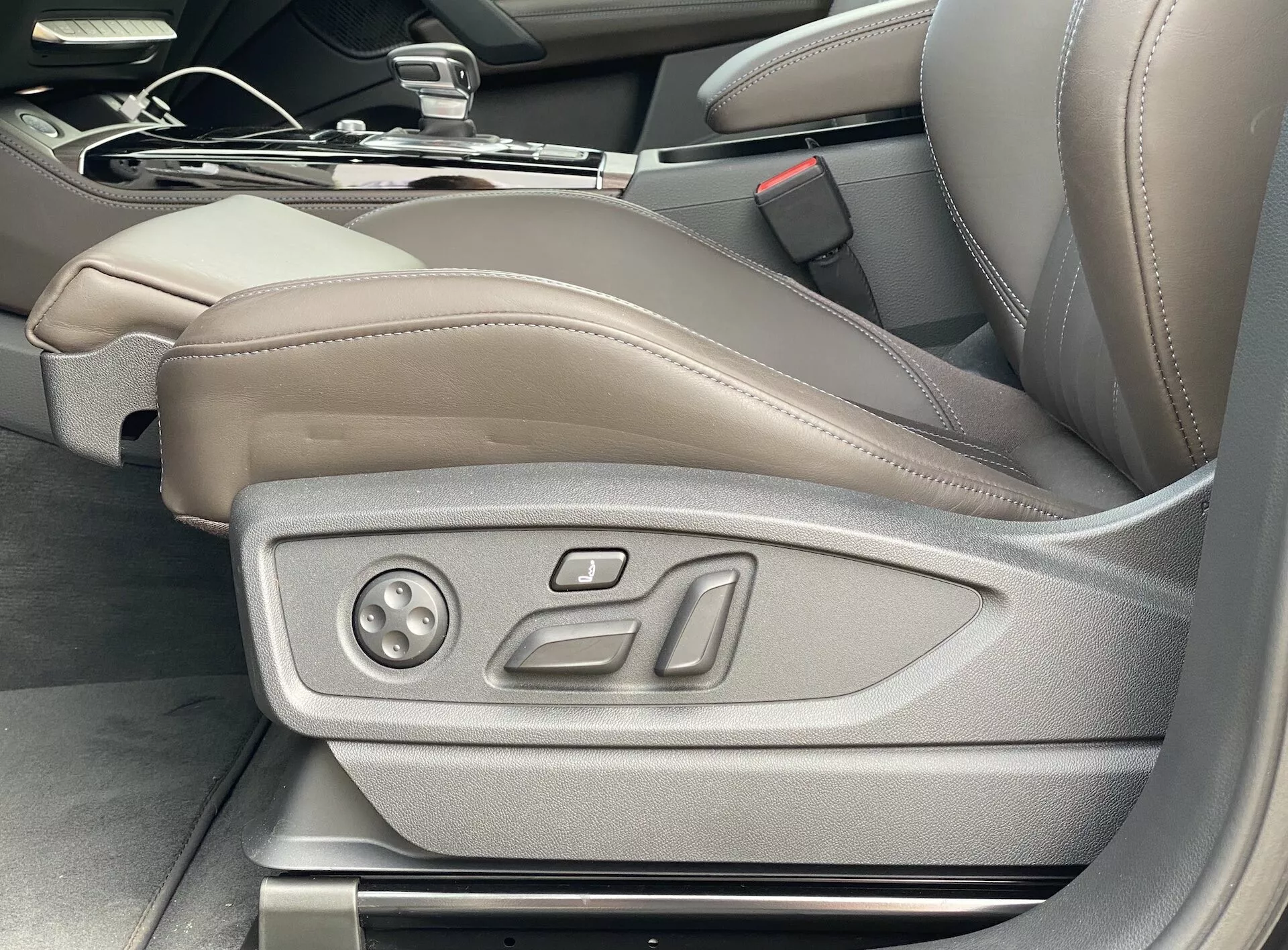 Pohľad do interiéru Audi Q5 2020 Sportback ukazuje sedadlo vodiča v svetlohnedej/béžovej koži s elektronickými ovládacími prvkami, ktoré zdôrazňujú luxus a pokročilú technológiu sedenia, vrátane potenciálnych pamäťových nastavení; snímka odobratá pod uhlom z vonkajšej strany vodičových dverí.