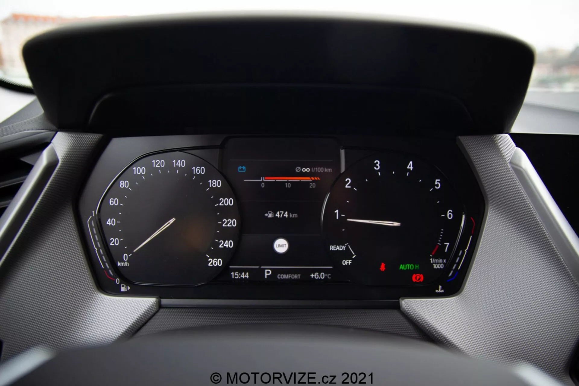 Detailný pohľad na digitálny prístrojový panel moderného automobilu BMW rad 1 2019 (BMW 116i), zobrazujúci podrobné údaje vrátane rýchlomera, otáčkomera, ukazovateľa paliva, teplotného ukazovateľa, digitálneho zobrazenia rýchlosti, zostávajúcej vzdialenosti s aktuálnym palivom, zobrazenia času (15:54), vonkajšej teploty (6.0 °C) a indikátorov automatických svetiel a parkovacej brzdy.