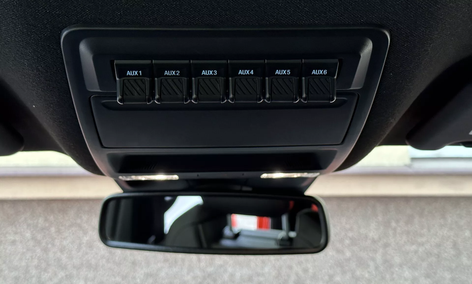 Zblízka pohľad do interiéru Ford Ranger 2022 s dôrazom na pomocné prepínače označené od AUX1 po AUX6 na stropnej konzole a štandardné spätné zrkadlo z pohľadu vodiča