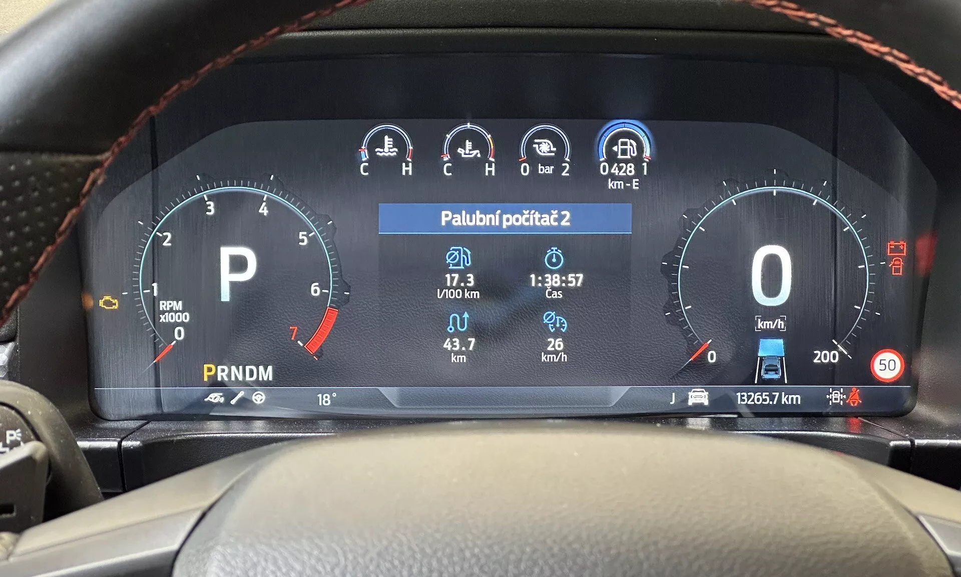Pohľad z vodičského sedadla na digitálny prístrojový panel Ford Ranger 2022 zobrazujúci otáčkomer, ukazovateľ paliva, rýchlosťomer, displej teploty a výber prevodovky na modernom palubnom paneli vozidla
