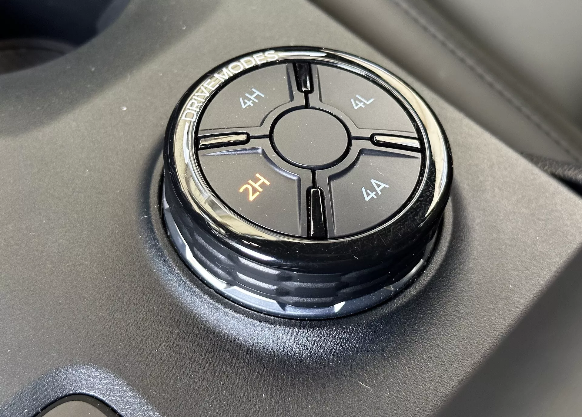 Detailný pohľad na volič jazdného režimu Ford Ranger 2022 na matnom čiernom povrchu, zobrazujúci možnosti jazdných režimov 4L, 4H, 2H a 4A s ostrým zaostrením a jemným odleskom