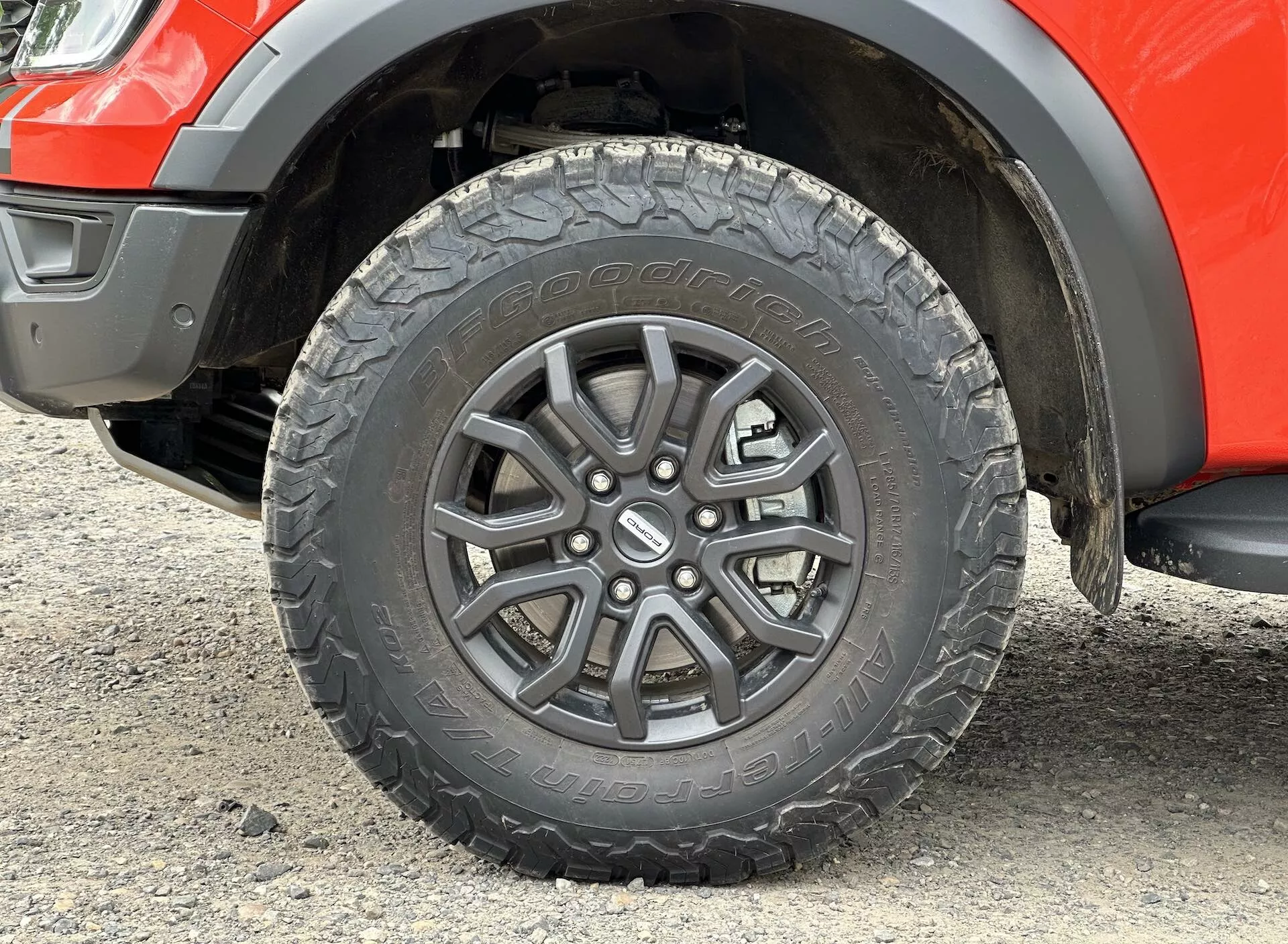 Detailné zobrazenie kolesa Ford Ranger 2022 s dizajnom z ľahkej zliatiny s viacerými špicami, dezénom pneumatiky pre všetky terény a časťou blatníka s viditeľnou svetlou výškou podvozka