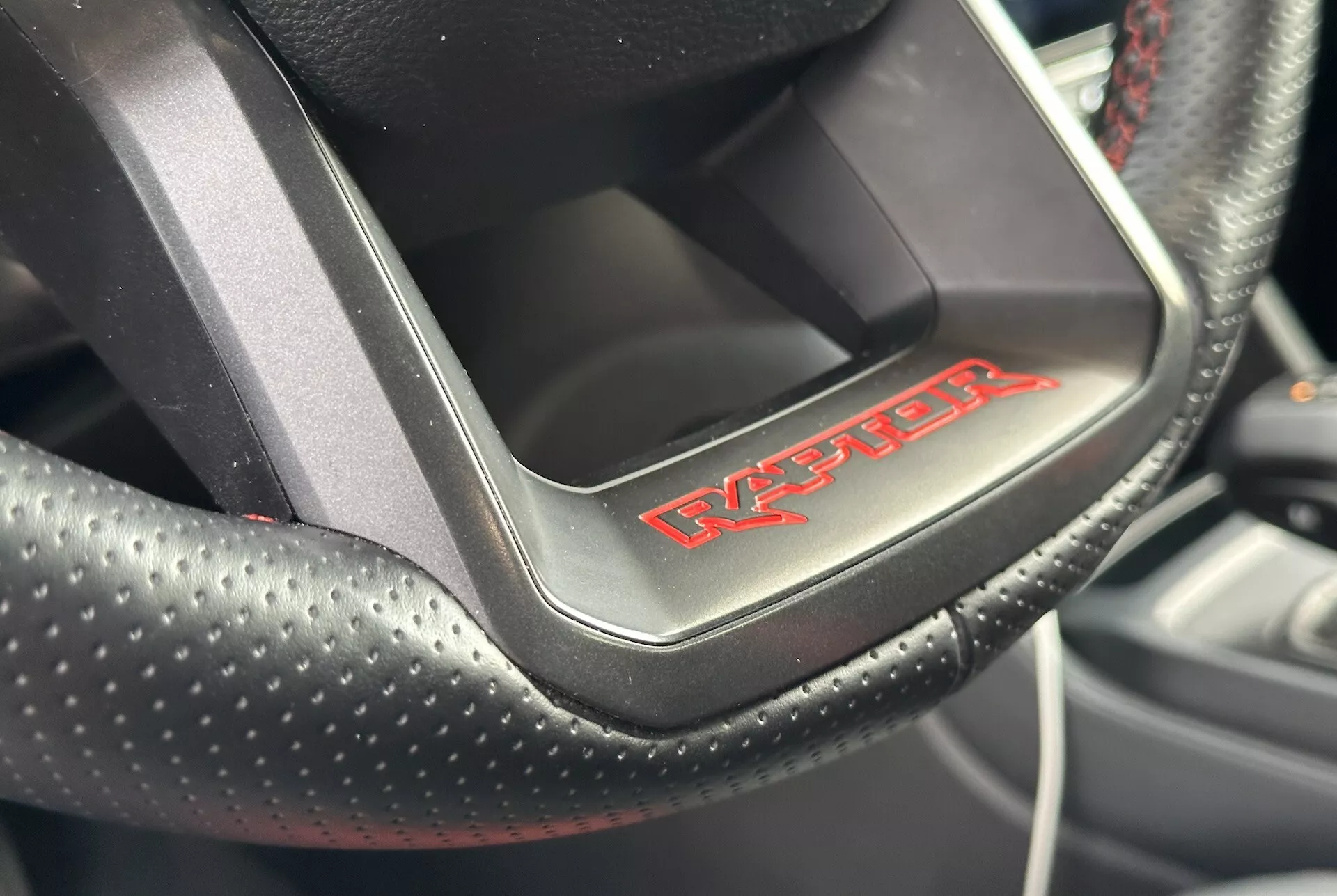 Detailný pohľad na volant Dodge Viper ukazujúci perforovanú kožu s červeným prešívaním a odznak 'Viper', čo naznačuje športovo luxusný interiér auta.