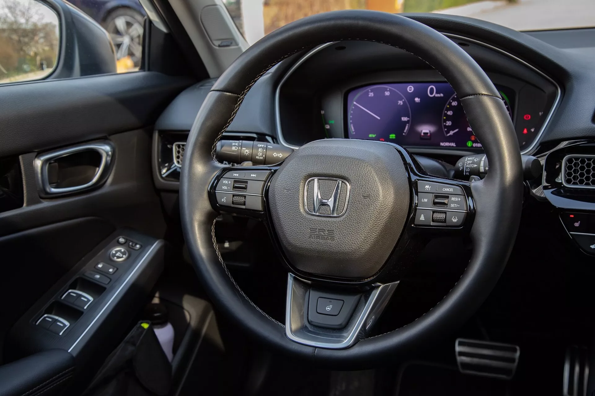 Interiérový pohľad Honda Civic 2022 z miesta vodiča, zdôrazňuje volant obalený kožou s multifunkčnými ovládačmi, digitálny prístrojový panel, časť stredovej konzoly s dotykovou obrazovkou a ovládacie prvky na dverách vodiča pre komplexné zobrazenie moderných technologických funkcií a luxusného dizajnu vozidla.