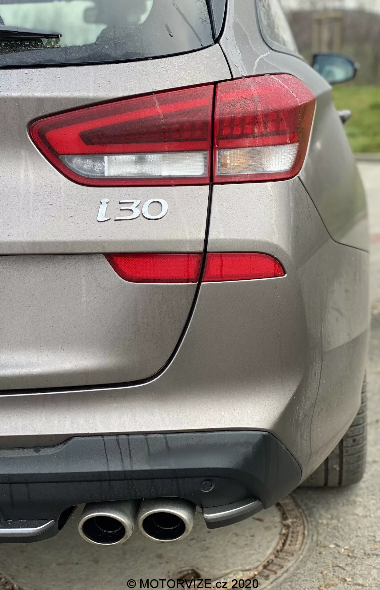 Detailný pohľad na zadnú časť strieborného Hyundai i30 2020 z uhla troch štvrtín, zdôrazňujúc ľavé zadné svetlo, zadný nárazník, štvoritý výfuk, označenie 't30' a metalický povrch laku, zdôrazňujúc dizajnové a výkonnostné detaily vozidla.