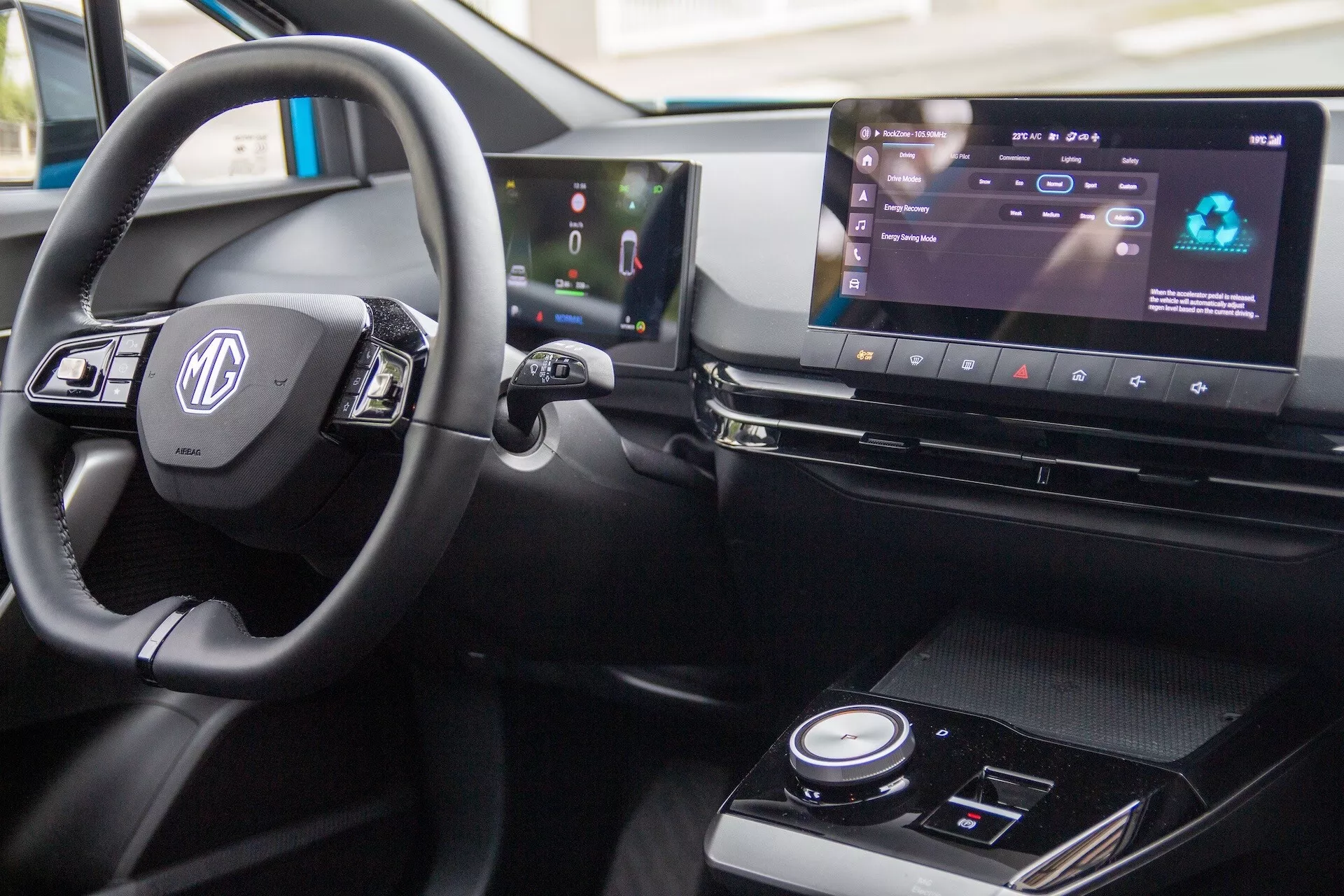 Detailný pohľad na interiér MG MG4 2022, predstavujúci volant s ovládacími prvkami, digitálny palubný panel a širokouhlý infotainment systém v pravostrannej konfigurácii