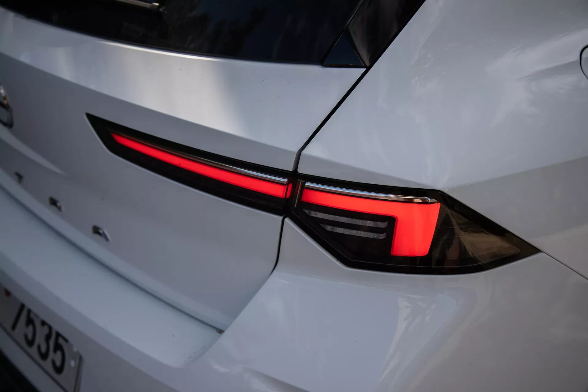 Detailný záber ľavého zadného svetla Opel Astra 2022 s moderným LED dizajnom a integráciou do bielej karosérie so športovým vzhľadom