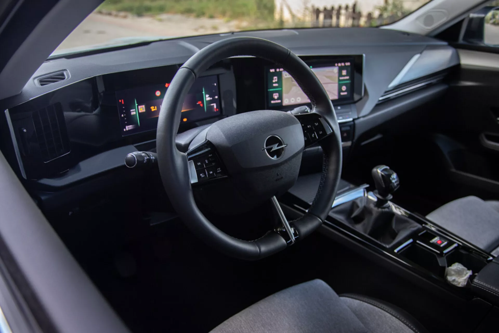 Interiér Opel Astra 2022 so sedadlom vodiča, technologicky pokročilým palubným panelom s logom Opel na volante, digitálnymi ukazovateľmi a dvojitými zvislými dotykovými panelmi