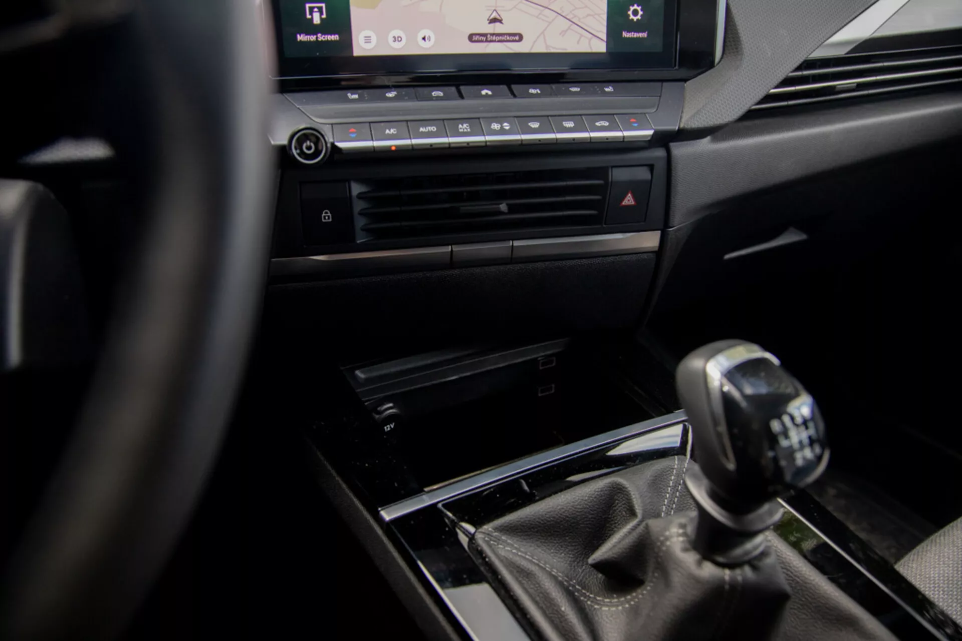 Interiérový pohľad na Opel Astra 2022 zameraný na stredovú konzolu a manuálne radenie z pohľadu vodiča, s volantom, luxusnými dizajnovými prvkami a moderným informačno-zábavným systémom.