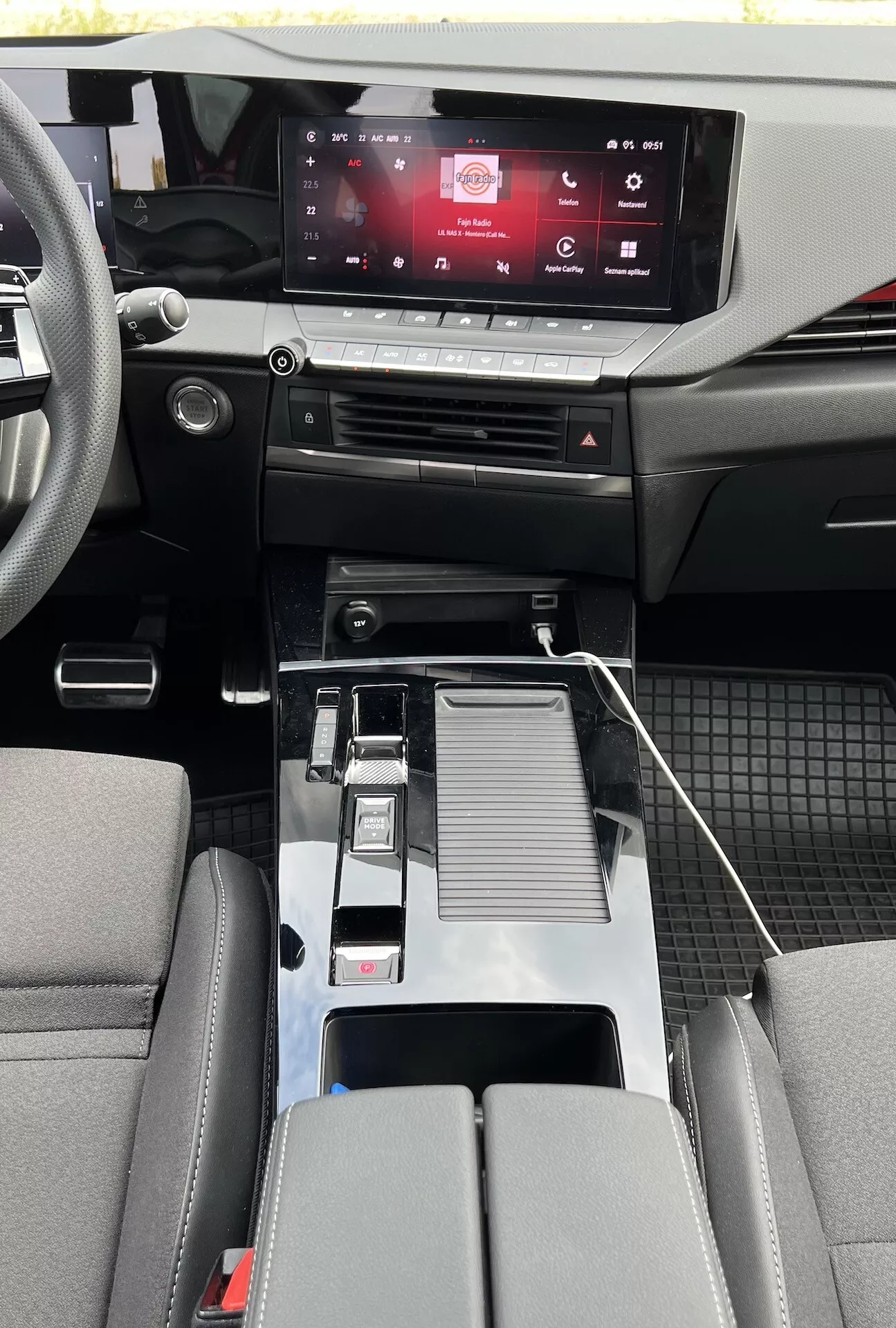Interiér Opelu Astra 2022 ukazujúci moderný dizajn kabíny s dotykovým informačným systémom, dotykovými ovládačmi klímy, kovovou radicou pákou, USB konektivitou, držiakmi na nápoje, detailne spracovanou stredovou opierkou, sedadlami v dvojfarebnom prevedení a detailmi kabíny z kombinácie materiálov s odolnými podlahovými rohožami