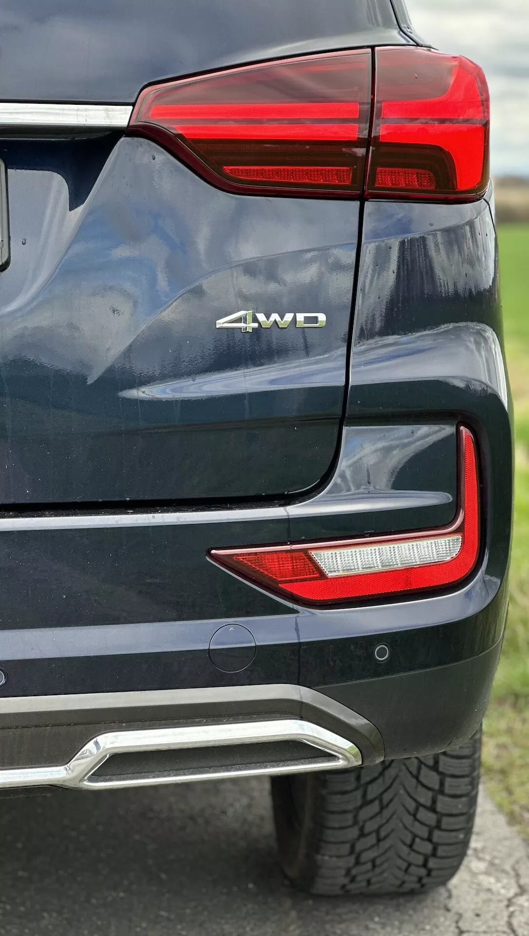 Detailný pohľad na zadný roh SsangYong Rexton 2021 ukazujúci LED zadné svetelné zoskupenie, odznak 4WD, parkovací senzor, integrovaný kryt výfuku v metalickej farbe