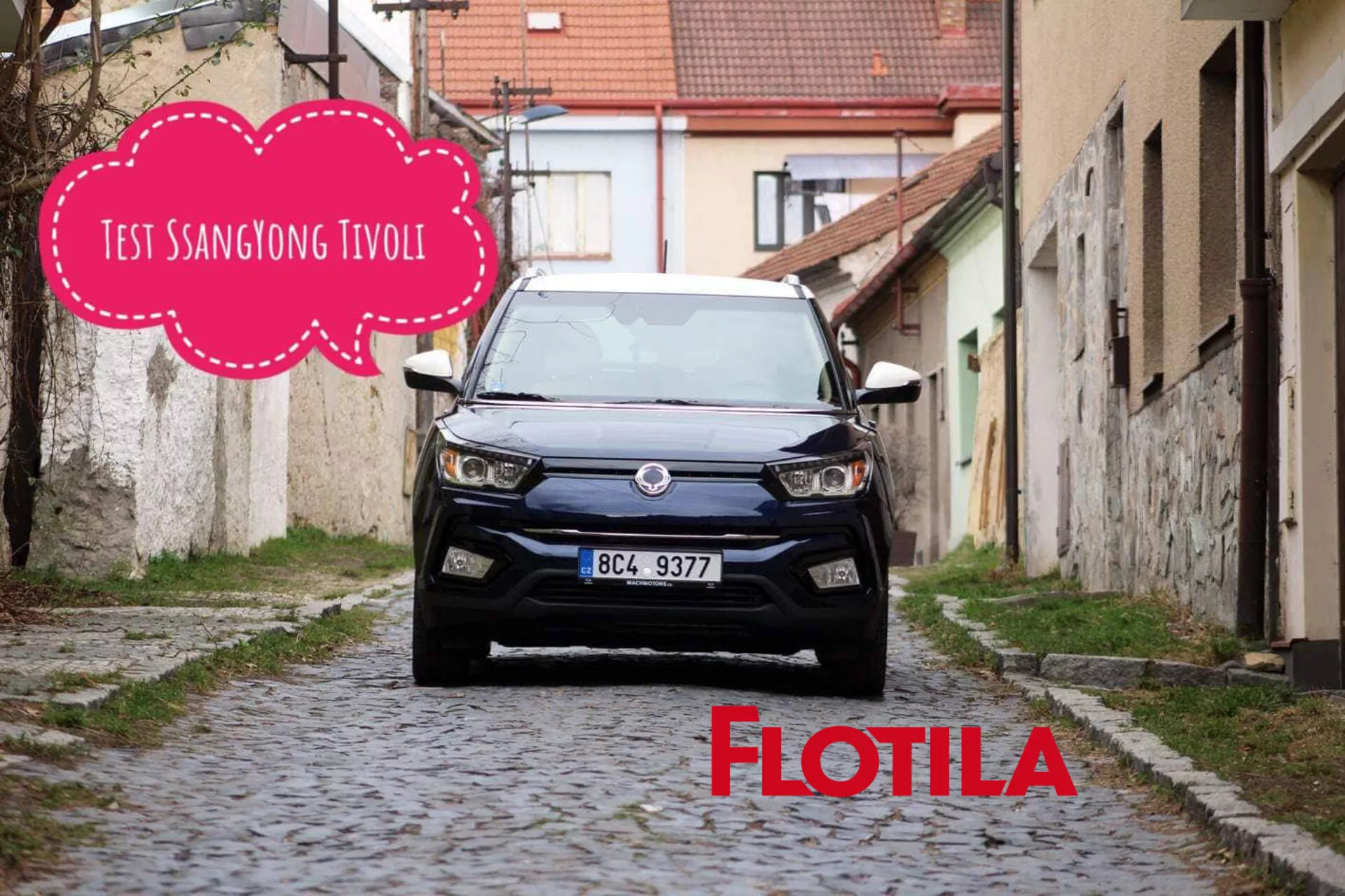 Čelný pohľad na model SsangYong Tivoli 2019 umiestnený v úzkej, vydláždenej európskej ulici, ktorý predstavuje modernú mriežku vozidla, LED svetlomety a súčasný dizajn kompaktného SUV, s grafikou myšlienkové bubliny čiastočne zakrývajúcou hornú strednú časť obrázka.