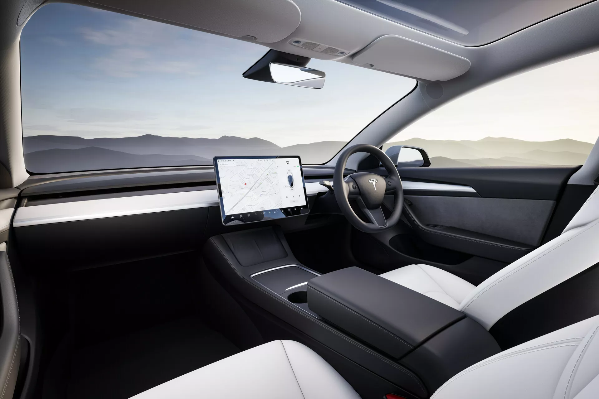 Pohľad na interiér Tesla Model 3 2019 z pohľadu zadného spolujazdca so zameraním na vodičovu stranu a stredovú konzolu. Obrázok ukazuje súčasné dizajnové prvky, ako sú dvere vodiča z rôznych materiálov, jednoduchý volant a veľký horizontálny dotykový displej v stredovej konzole, naznačujúci moderný infotainment systém vozidla. Absencia tradičného prístrojového panela naznačuje digitálny prístrojový panel alebo HUD technológiu. Dvojfarebné čalúnené sedadlá a minimalistický dizajn odrážajú prémiové vlastnosti elektrického modelu vozidla.