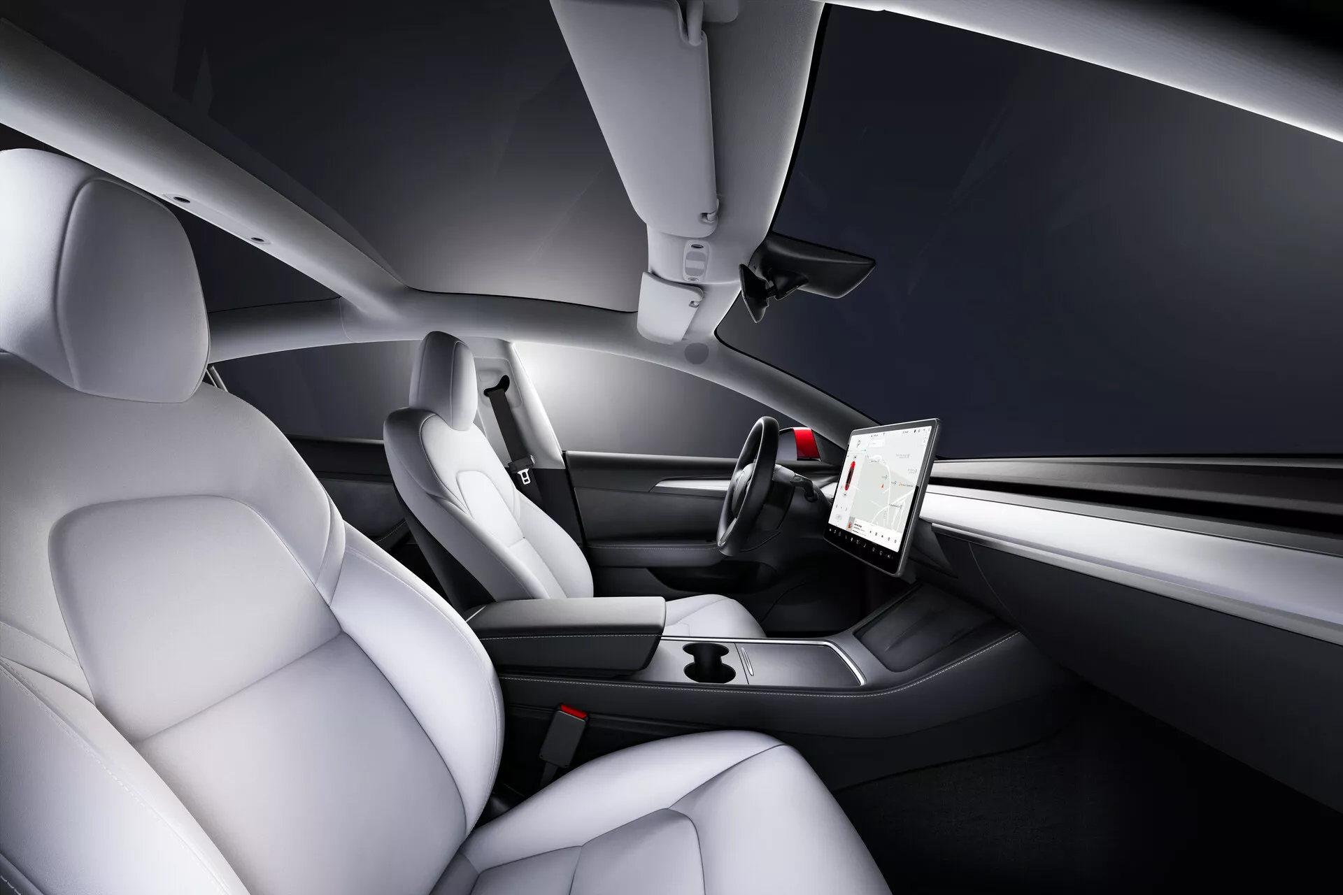 Pohľad na interiér Tesla Model 3 z roku 2019, prvej generácie, zvýrazňujúci oblasť vodiča a spolujazdca z vyvýšenej zadnej perspektívy. Funkcie zahŕňajú svetlé, tvarované, kožené sedadlá pre komfort a bočnú oporu, výrazný zvislý dotykový displej pre multimédiá a nastavenia vozidla, elegantnú minimalistickú prístrojovú dosku s integrovanými ovládacími prvkami, športovo vyzerajúci trojramenný volant s multifunkčnými tlačidlami a úzku stredovú konzolu s minimalistickými dizajnovými prvkami a držiakmi na poháre.