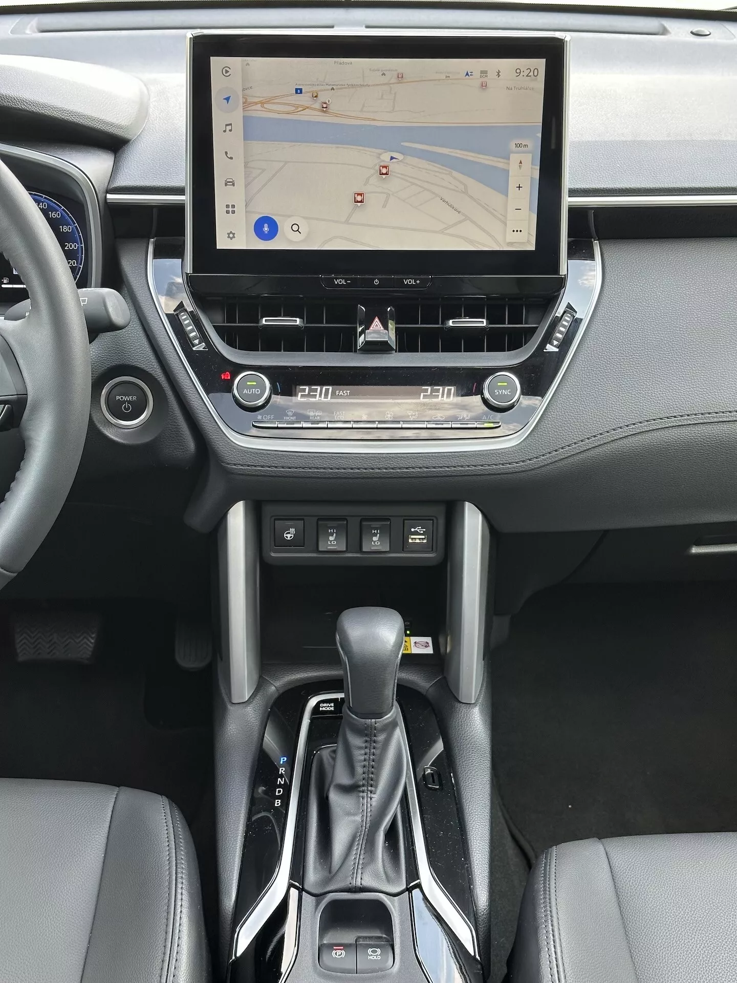 Interiér Toyota Corolla Cross 2022 s dotykovým informačným systémom s GPS navigáciou, dvojzónovou klimatizáciou, slotom pre CD, tlačidlami na ovládanie médií a telefónu, modernou automatickou radiacou pákou a akcentmi z kože na stredovej konzole a dizajne palubnej dosky