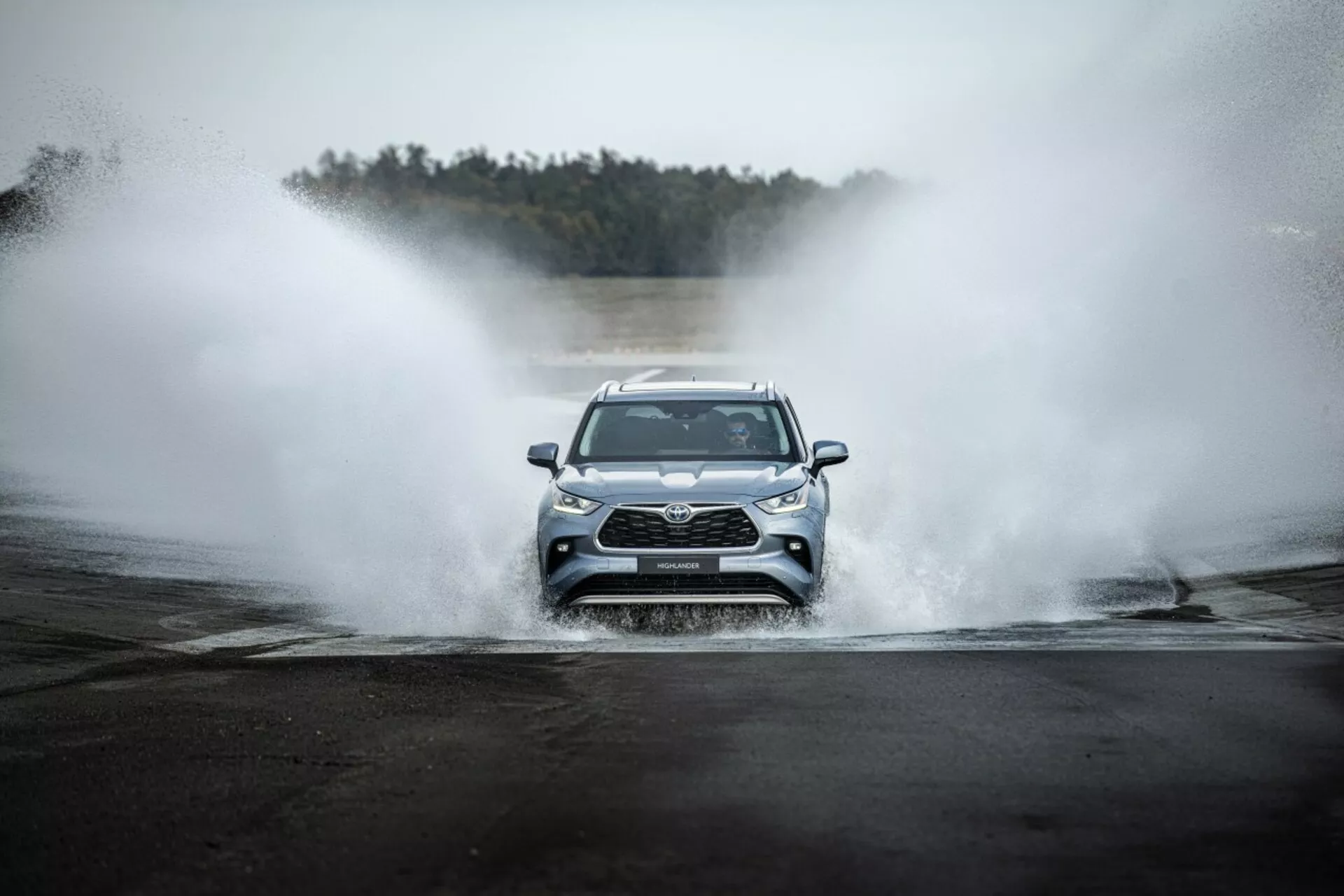 Toyota Highlander 2021 idúca čelne cez vodu, predvádzajúca prednú mriežku, LED svetlomety a športový dizajn v dobrodružnom prostredí