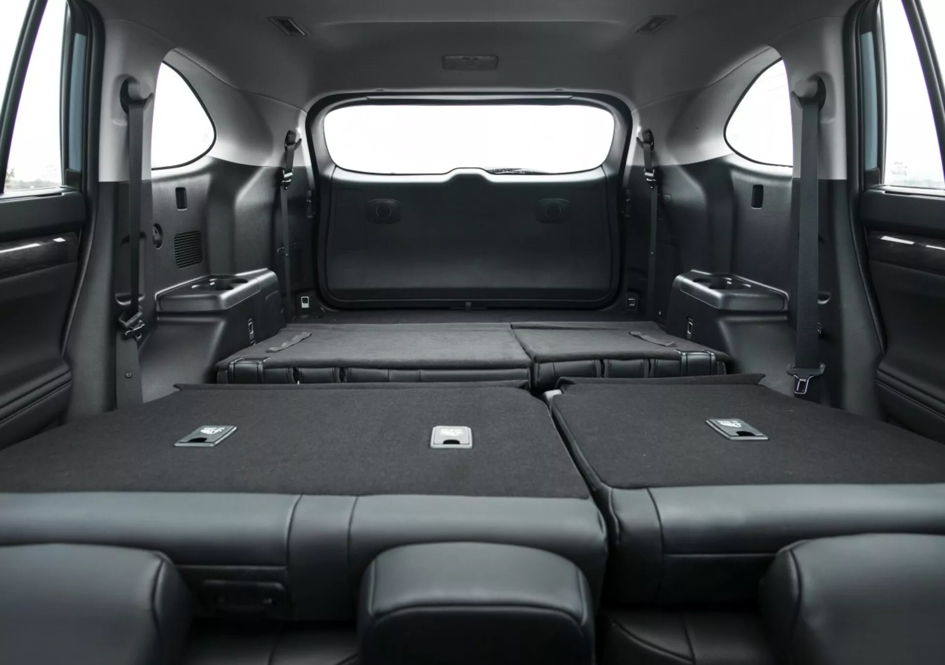 Interiér Toyota Highlander 2021, zobrazujúci rozšírený nákladný priestor so sklopenými zadnými sedadlami, ktoré zdôrazňuje priestrannú kapacitu batožiny a elegantné čierne čalúnenie z vnútornej perspektívy.