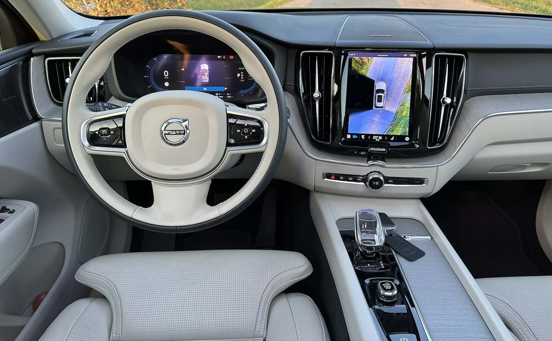 Interiér Volvo XC60 Recharge Plug-in Hybrid 2021 z pohľadu zo zadného sedadla, zobrazujúci palubnú dosku, digitálne displeje, multifunkčný volant a stredovú konzolu