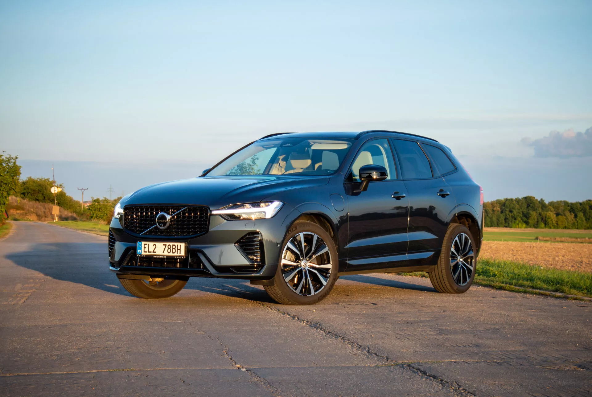 SUV strednej veľkosti Volvo XC60 Recharge Plug-In Hybrid z roku 2021 v štýlovom a športovom dizajne, s LED svetlometmi Thor's Hammer, pokročilými zliatinovými kolesami a sochárskou prednou mriežkou, zachytené v teplom popoludňajšom svetle z uhla tri štvrtiny spredu, ktoré ukazuje dynamický bočný profil a prednú fasádu.