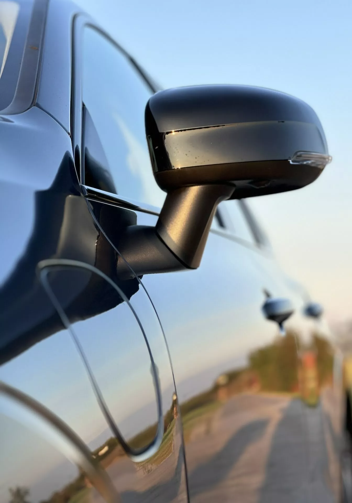 Detailný pohľad na bokové zrkadlo Volvo XC60 Recharge Plug-In Hybrid 2021 s elegantným dizajnom, integrovaným smerovým ukazovateľom a uchytením k dverám auta, čo zdôrazňuje technológiu a bezpečnostné prvky automobilov.