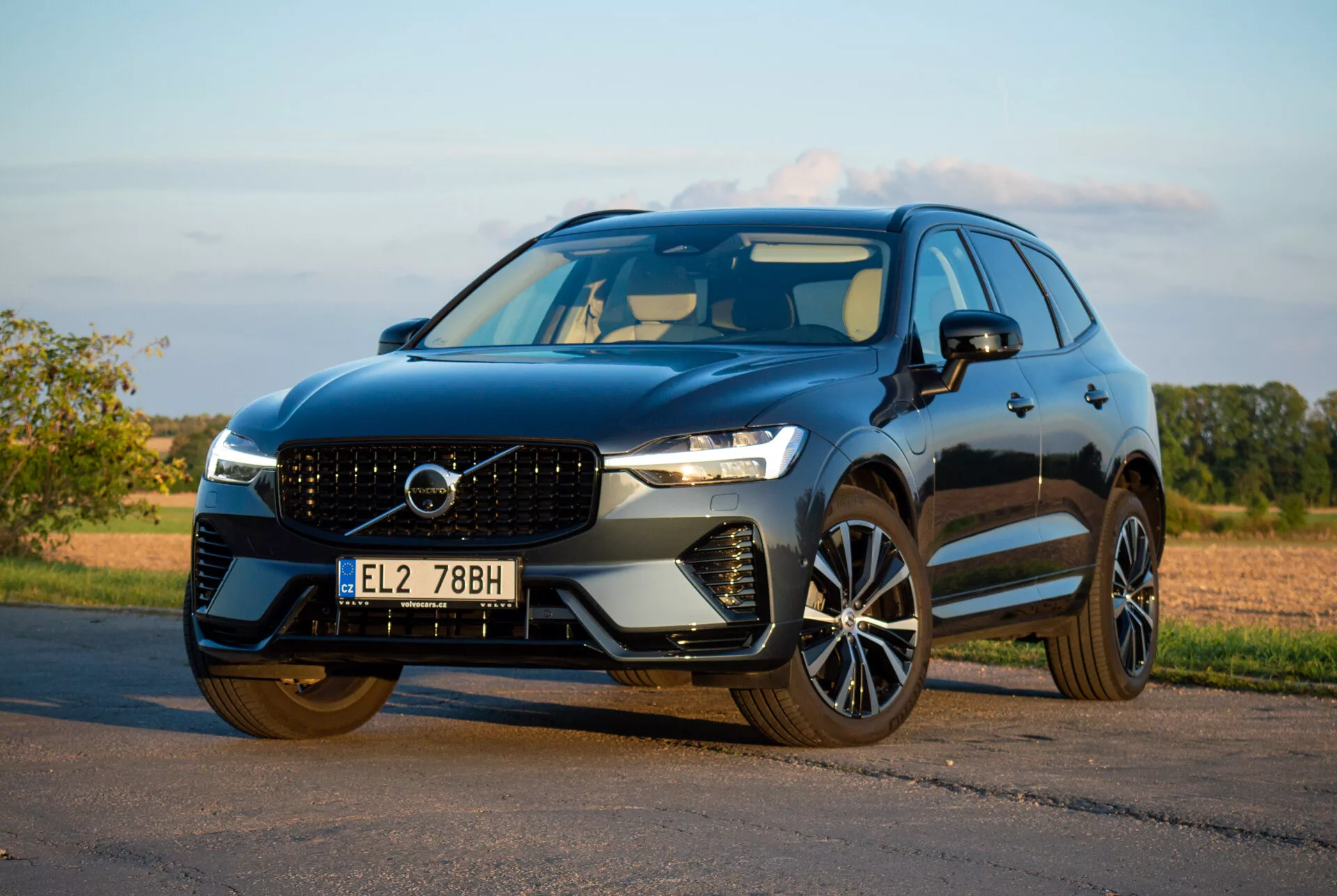 SUV Volvo XC60 Recharge Plug-In Hybrid 2021 zaparkované na asfalte, predvádza svoj elegantný dizajn a pokročilé technologické funkcie z nízkeho uhla z troch štvrtín spredu