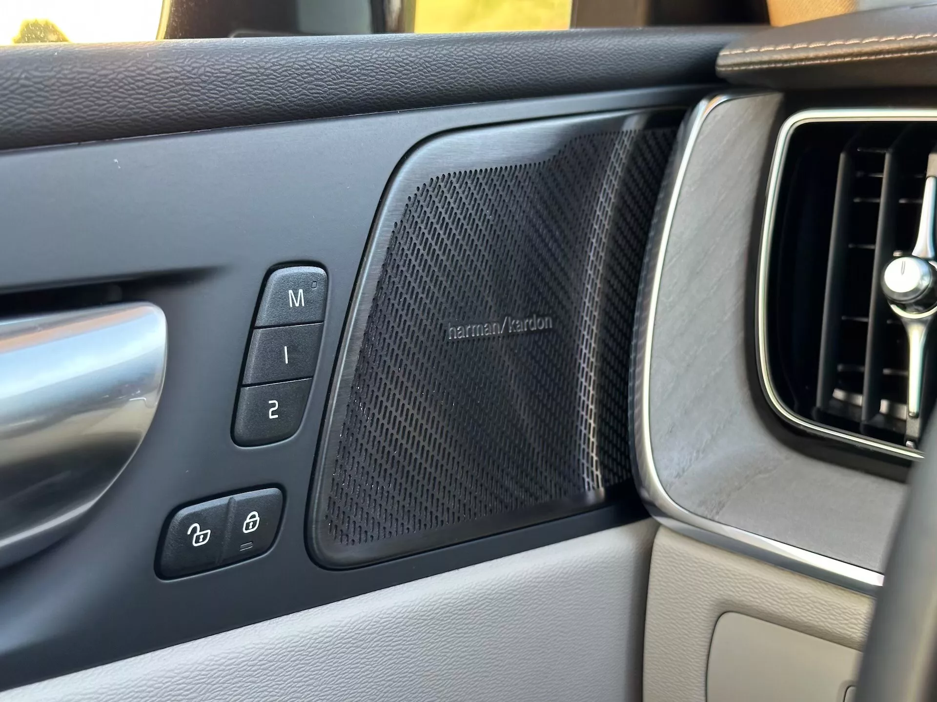 Interiér Volvo XC60 Recharge Plug-In Hybrid 2021 s pohľadom na panel dverí vodiča, vrátane nastavení pamäte sedadiel, ovládania elektronického zámku dverí, mriežky reproduktoru harman/kardon a časti mriežky ventilácie palubnej dosky