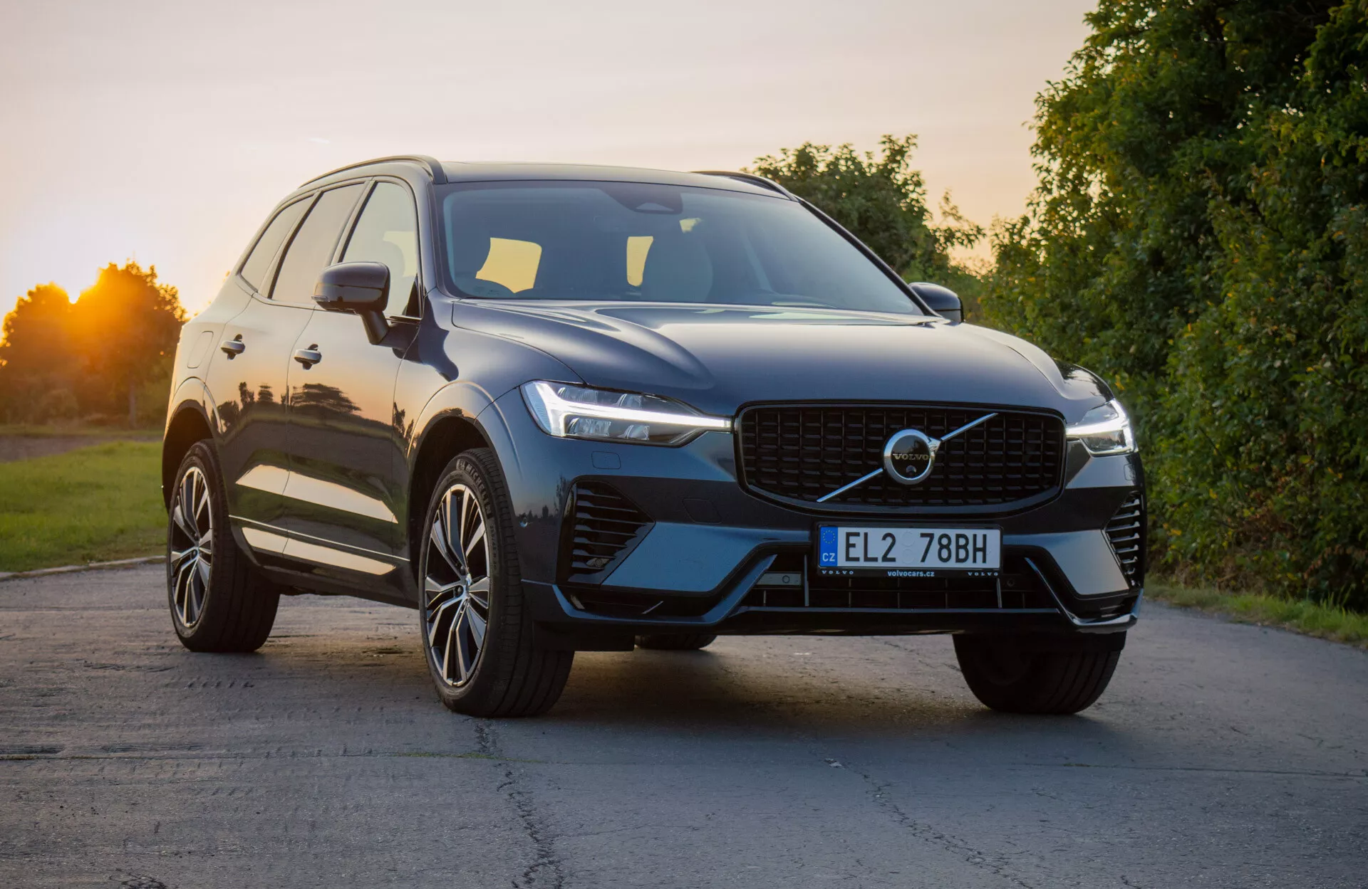 Volvo XC60 Recharge Plug-In Hybrid 2021 v modernom dizajne SUV, mierne naklonené k zvýrazneniu prednej časti, ukazuje výraznú mriežku, štíhle LED svetlomety a aerodynamický predný nárazník s integrovanými vstupmi vzduchu, doplnený lesklým vonkajším dokončením a prémiovými zliatinovými kolesami s viacerými lúčmi pri prirodzenom dennom svetle.
