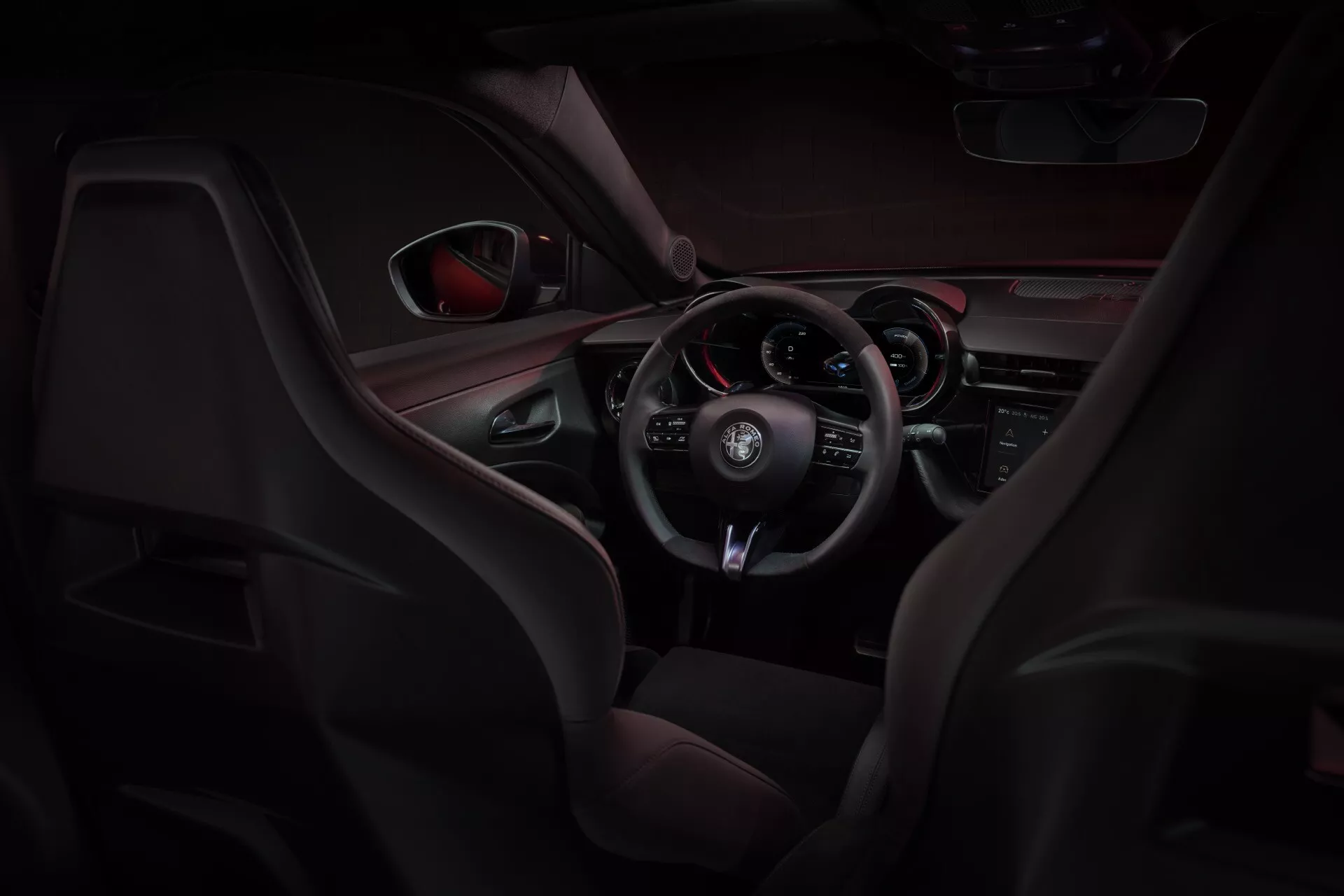 Interiér Alfa-Romeo Junior (966) pre rok 2024 ukazujúce športové sedadlá z kože a sieťoviny, multifunkčný volant obalený kožou a palubnú dosku orientovanú na vodiča s červeným akcentovým osvetlením