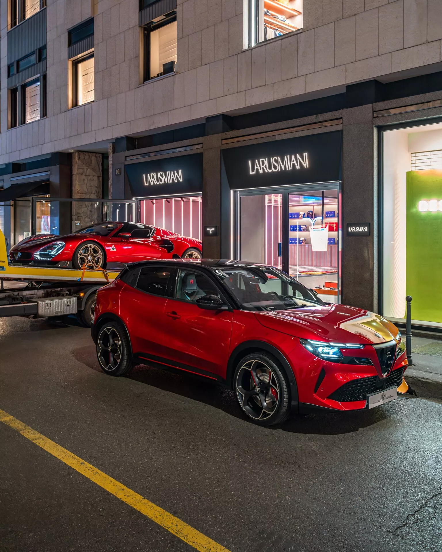 Alfa Romeo Junior 2024 v jasne červenej SUV zaparkované na osvetlenej mestská ulica v noci, predvádza štýlový dizajn, LED svetlomety a zliatinové kolesá z pohľadu z prednej trojštvrte