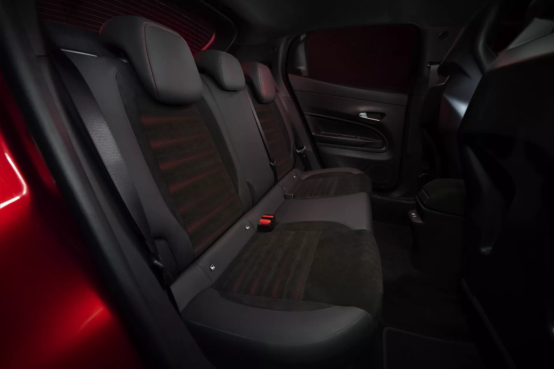 Interiérový pohľad na Alfa Romeo Junior (966) pre rok 2024 s dôrazom na zadnú cestujúcu časť s lavicou pre tri osoby, kombinované čalúnenie a jemné červené ambientné osvetlenie