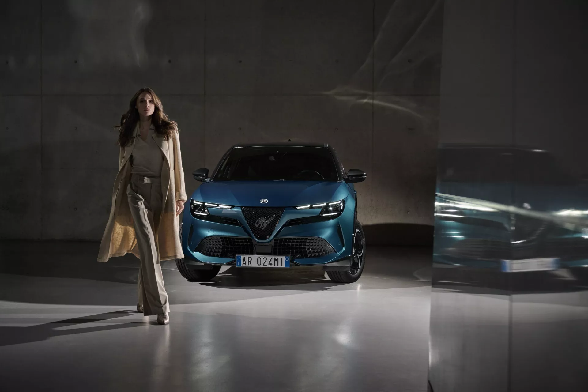Alfa-Romeo Junior 2024 fotografovaný z nízkeho predného uhla zvýrazňujúci mriežku, LED svetlomety a moderný predný fasádny dizajn v hlboko metalickej modrej, zdôrazňujúci pokročilú technológiu osvetlenia a dizajn v mestskom prostredí