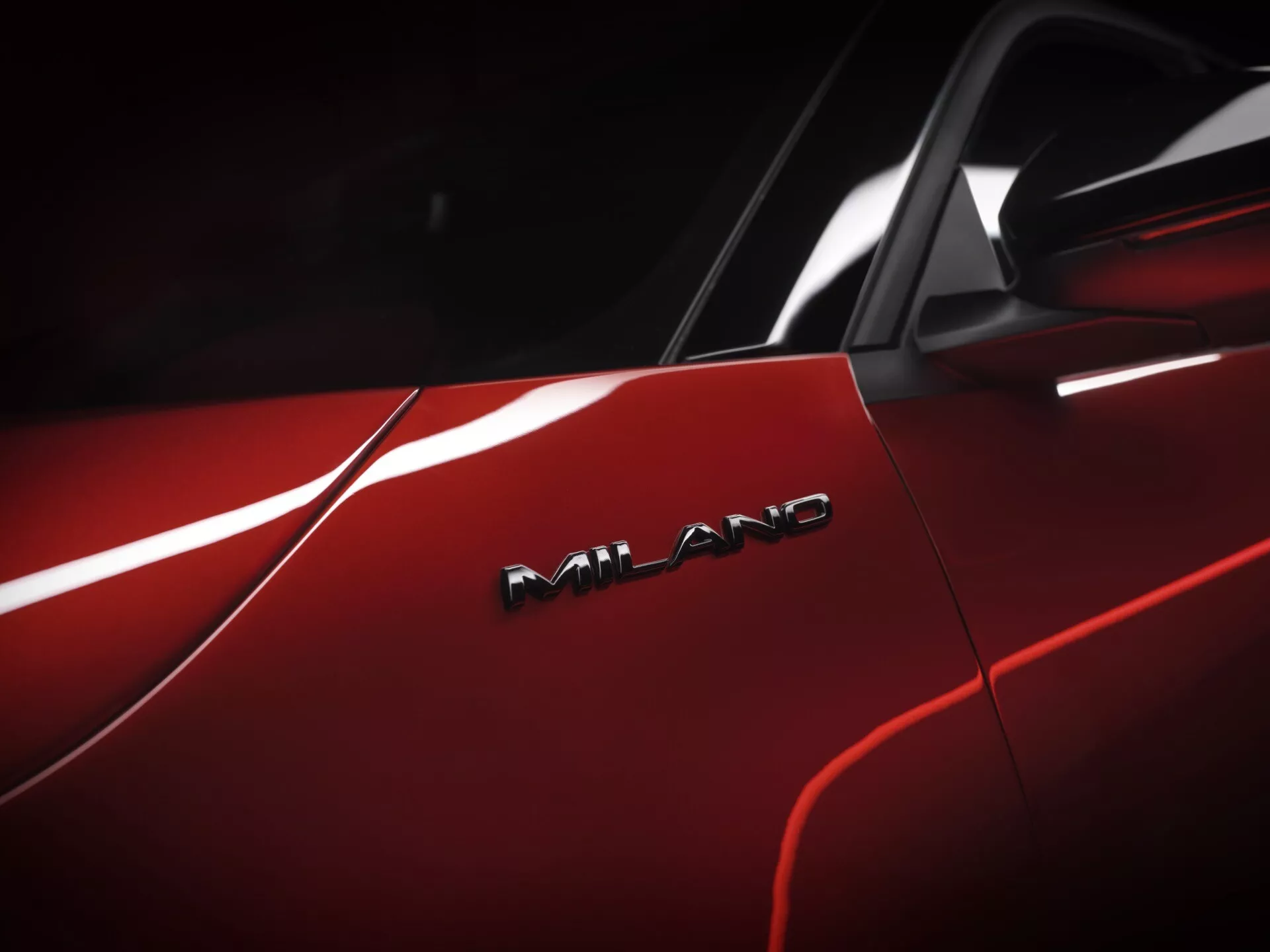 Detailný pohľad na červený Alfa-Romeo Junior 2024 s lesklým povrchom a odznakom AMG, čo naznačuje jeho vysokú výkonnosť a nadradený dizajn