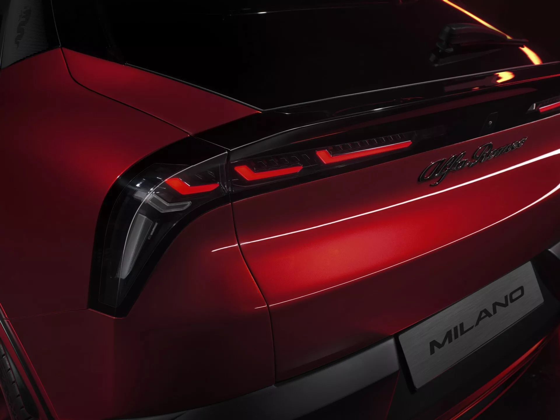 Detailný pohľad na zadnú časť vozidla Alfa Romeo Junior 2024, zobrazujúci LED zadné svetlá, odznak Lamborghini Milano, v metalickej červenej