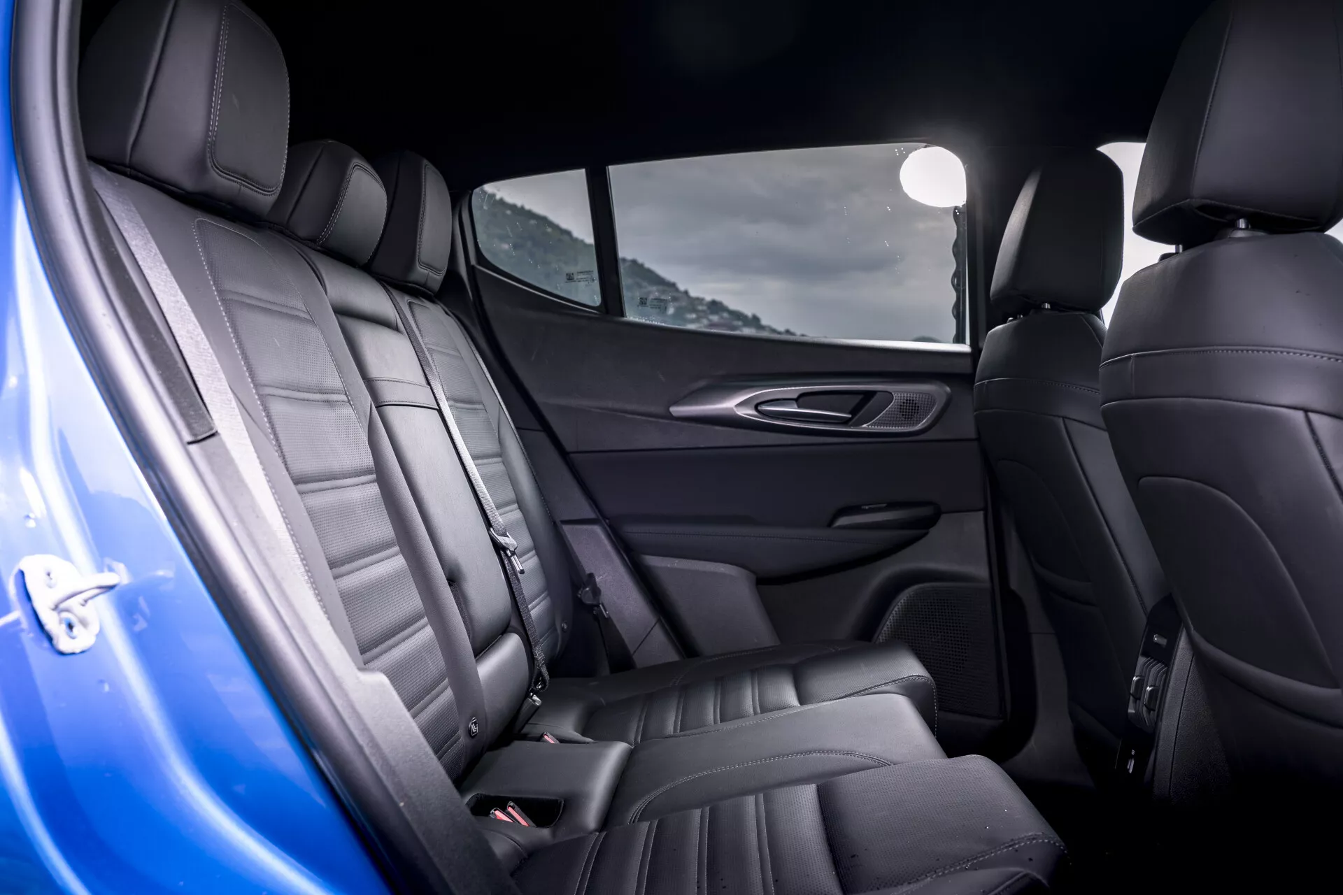 Interiér Alfa-Romeo Tonale 2022 s luxusnými koženými zadnými sedadlami s detailným prešívaním a ergonomickým dizajnom, vrátane dverí, zdôrazňujúci prémiové funkcie