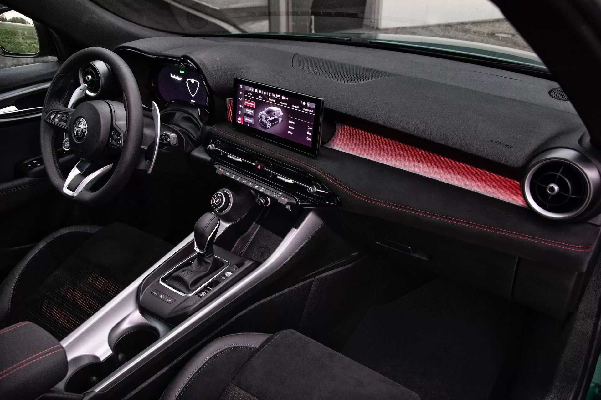 Interiér Alfa Romeo Tonale 2022 s modernou palubnou doskou, digitálnym infotainment centrom, akcentmi z uhlíkových vlákien a sedadlami so šerveným prešívaním, pohľad z perspektívy spolujazdca