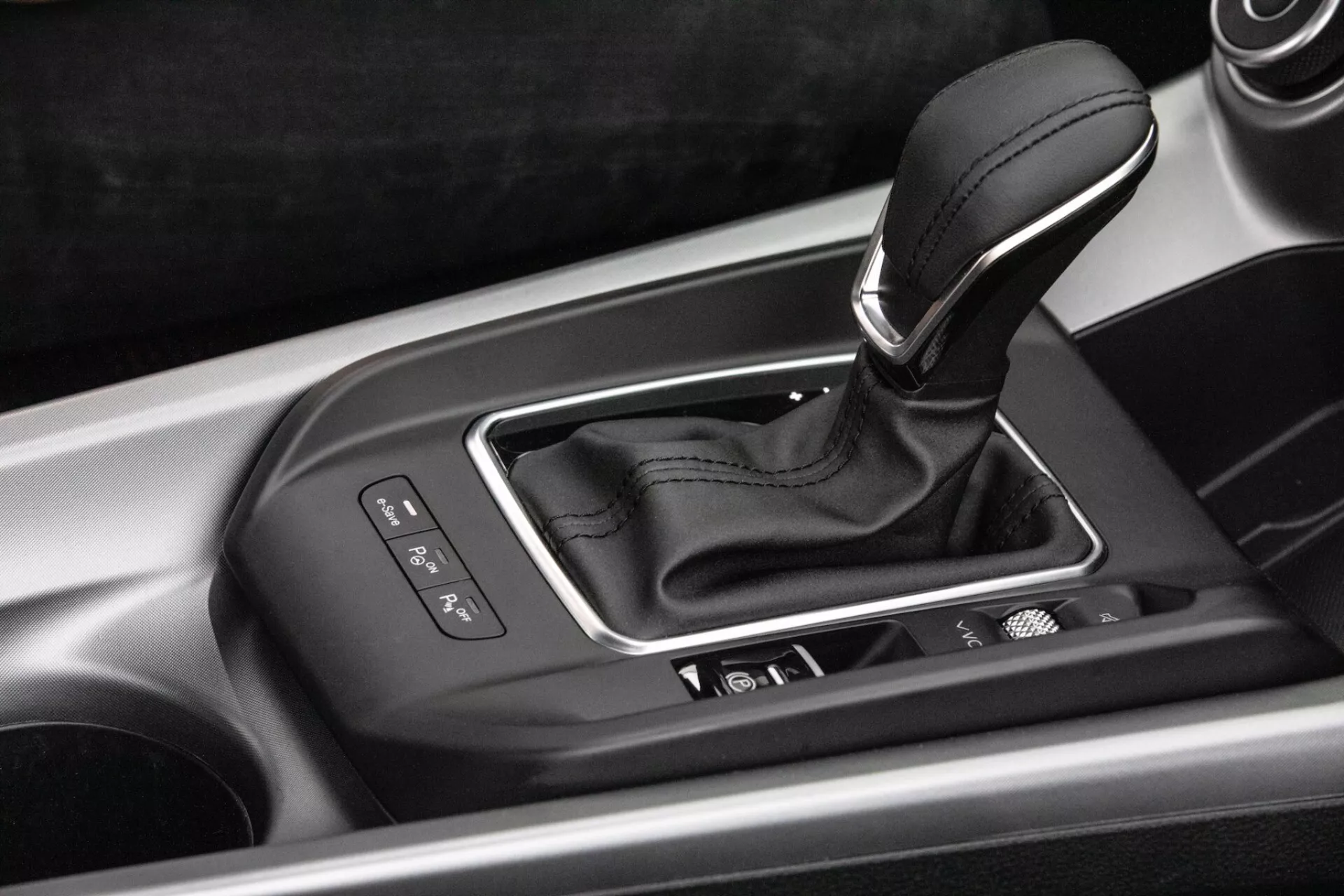 Detailný vnútorný pohľad na stredovú konzolu Alfa-Romeo Tonale 2022 s pákou automatickej prevodovky v striebornom puzdre s ukazovateľmi výberu prevodov, integrovanými ovládacími tlačidlami a vypracovaním vysokej kvality