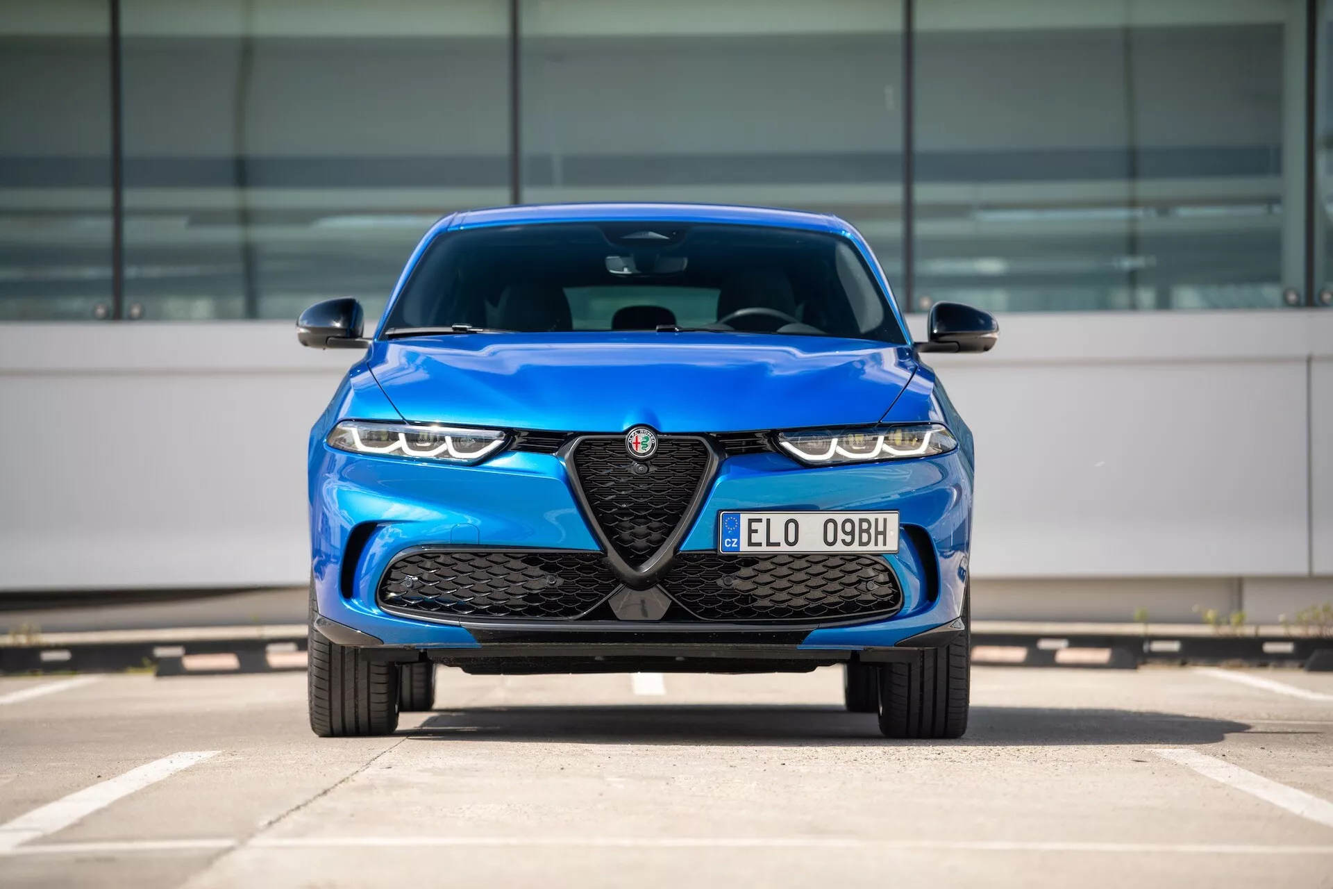 Modré Alfa Romeo Tonale 2022, pohľad spredu na parkovisku zobrazujúci mriežku s emblémom, LED svetlomety a aerodynamické dizajnové prvky