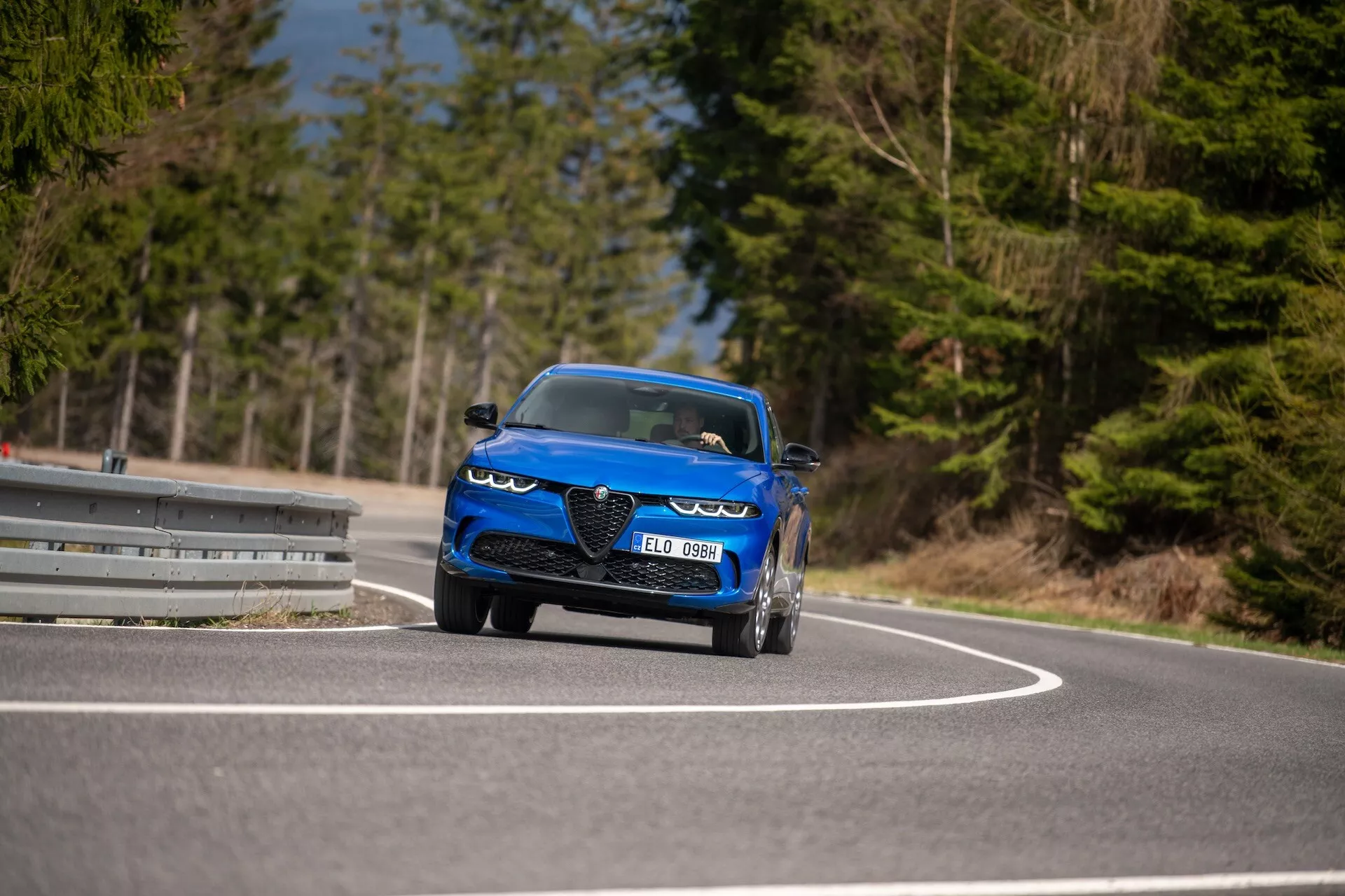 Alfa-Romeo Tonale 2022 v pohybe na zákrute, prezentujúce jeho dynamický dizajn, LED svetlomety, prívody vzduchu, športový kabriolet štýl a luxusné prvky z nízkeho uhla pohľadu z trojštvrte prednej perspektívy