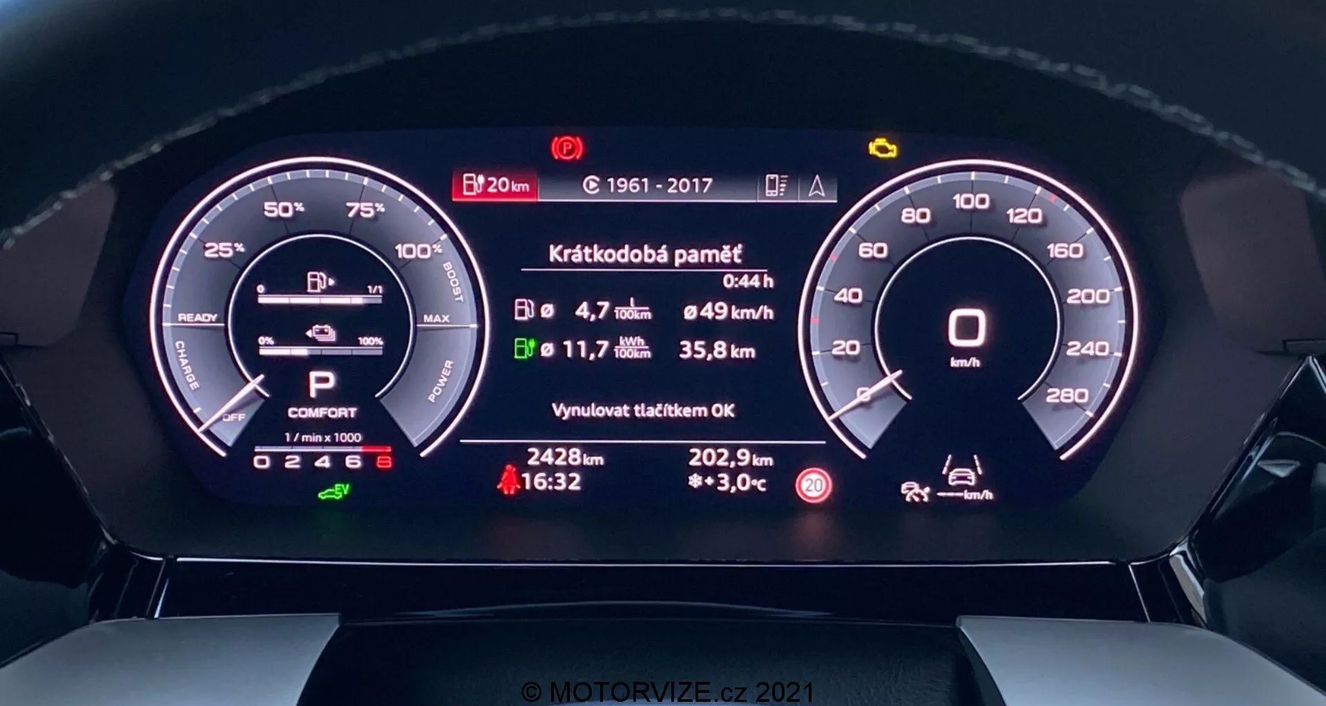 Detailný pohľad na digitálny prístrojový panel Audi A3 2020 Sportback z miesta vodiča. Priamy pohľad ukazuje detailné digitálne displeje otáčkomera, indikátora batérie, výberu prevodovky, jazdného režimu, priemernej rýchlosti, spotreby paliva, vzdialenosti do vyprázdnenia nádrže, vonkajšej teploty a stavu správ o nedávnej údržbe. Moderný dizajn integruje digitálne a analógové prvky pre technologicky pokročilý a intuitívny zážitok.