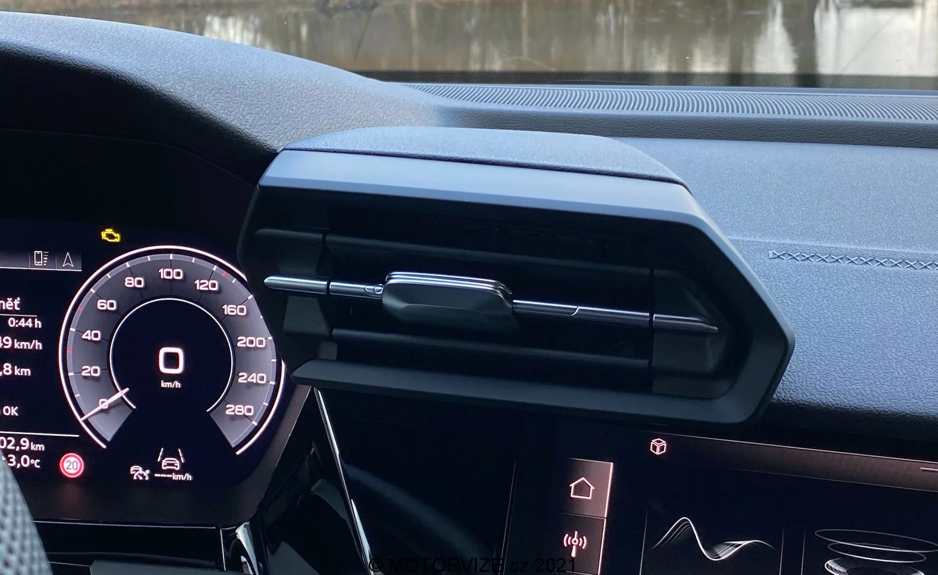 Pohľad na interiér modelu Audi A3 Sportback 2020 z miesta vodiča, zobrazujúci digitálny prístrojový panel, elegantný dizajn palubnej dosky so zatvoreným centrálnym vetraním a dekoračnými prvkami, okraj infotainment displeja, luxusné kožené materiály s prešívaním, ambientné osvetlenie a čiastočne viditeľný volant s možnými ovládacími prvkami, zdôrazňujúc modernú automobilovú technológiu a luxusný dizajn.
