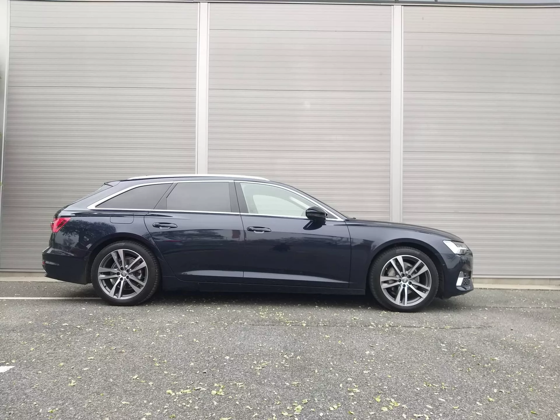 Bočný profil moderného kombi Audi A6 2018 s predvedením elegantného dizajnu, pokročilých technológií a prémiových zliatinových kolies, zaparkovaný v priemyselnom prostredí