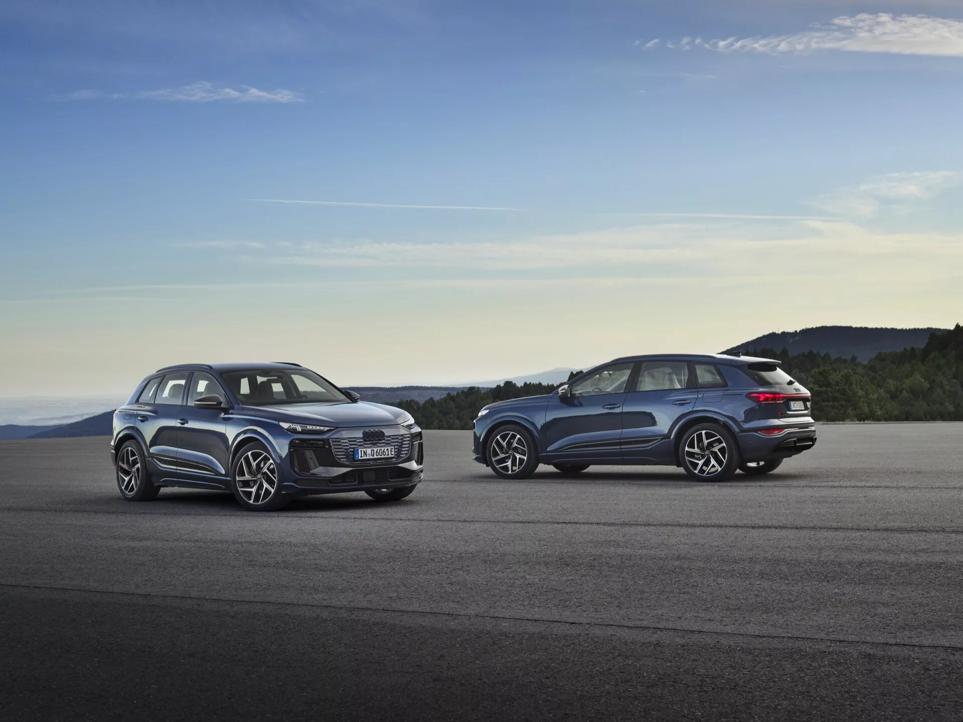 Audi Q6 e-tron 2024 (GF) zaparkovaný pri západe slnka, ktorý ukazuje jeho elegantný aerodynamický dizajn, futuristické LED svetlomety, priestranný interiér, veľké zliatinové kolesá a pokročilý elektrický pohon.