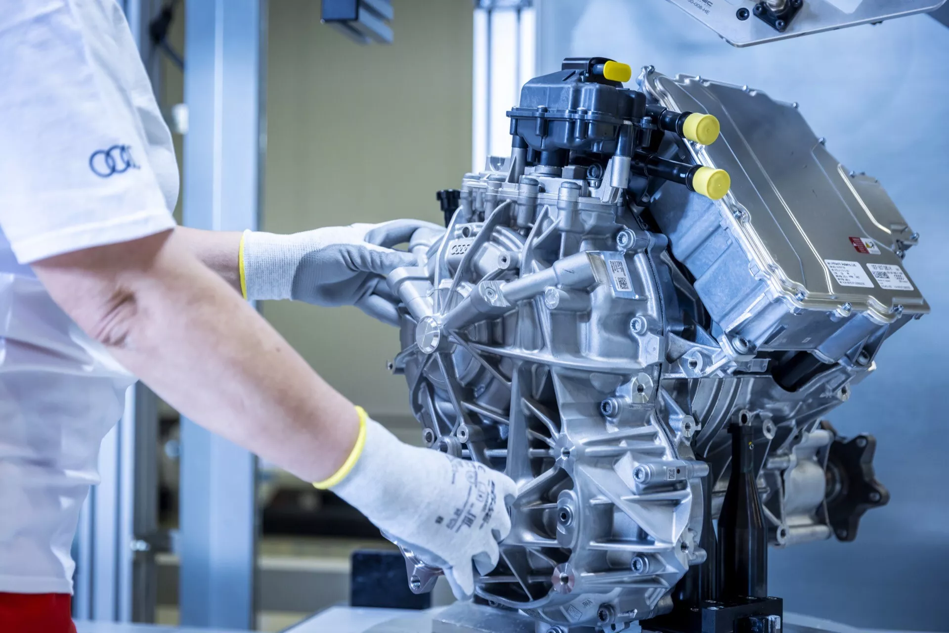 Detailný pohľad na moderný výkonný motor s technikom kontrolujúcim ho v čistom priemyselnom prostredí, zdôrazňujúci komponenty ako je sací kolektor a zapaľovacie cievky.
