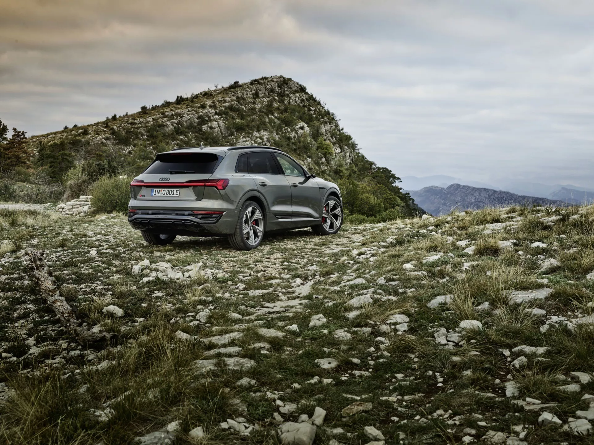 Audi Q8 e-tron 2023 s metalickým povrchom, umiestnené v drsnej vonkajšej teréne, predvádzajúce schopnosti na ceste mimo ciest, športovo-praktický dizajn so zadnými LED svetlami, zliatinovými kolesami a pokročilými technologickými vlastnosťami