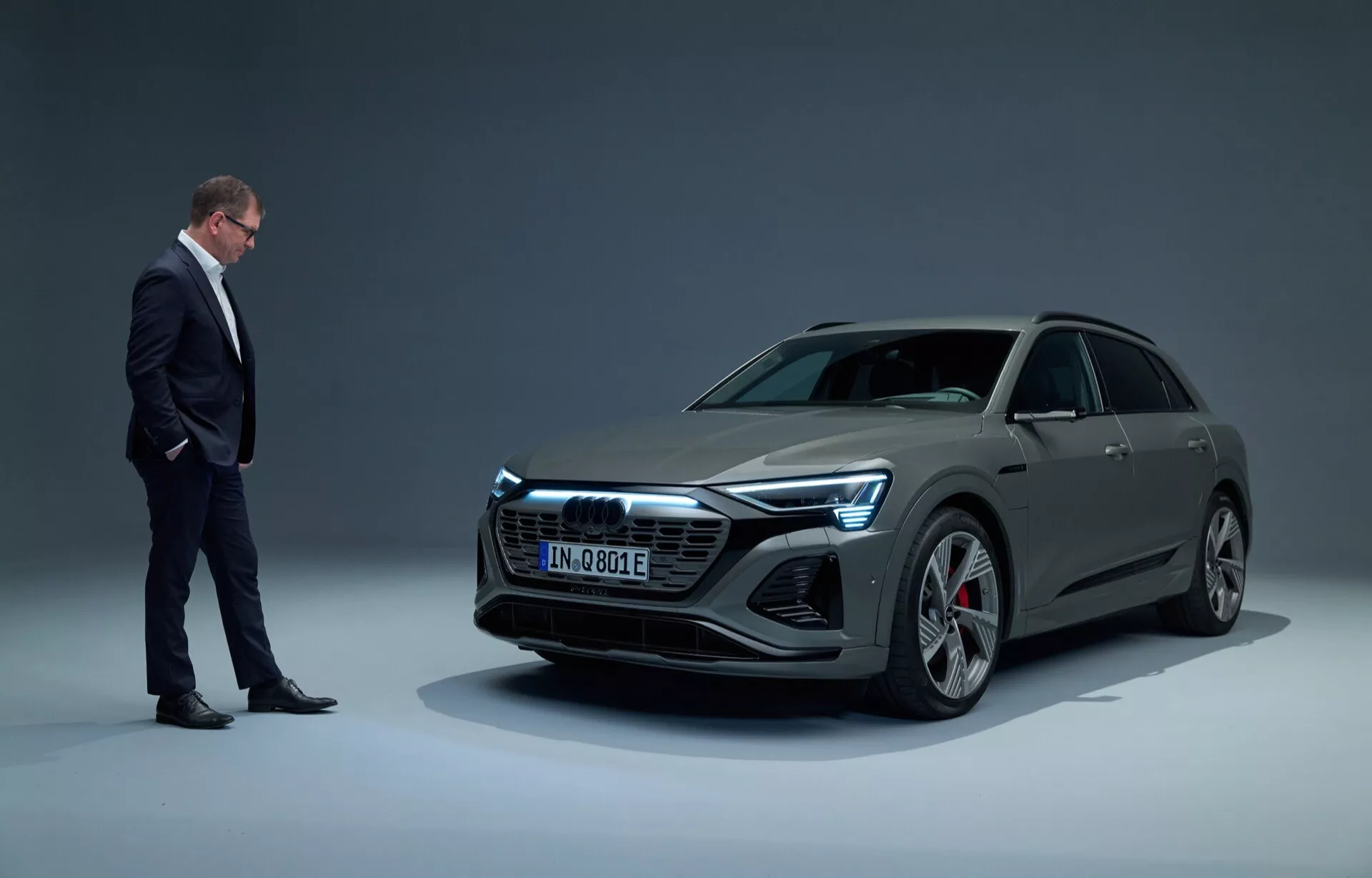 Audi Q8 e-tron 2023 v štúdiovom nastavení, ukazujúce moderné elektrické luxusné vozidlo so štíhlym dizajnom, zobrazené z nízkeho uhla trojštvrťového predného pohľadu na pozadí s prechodom, s úplnými LED svetlometmi a veľkými zliatinovými kolesami