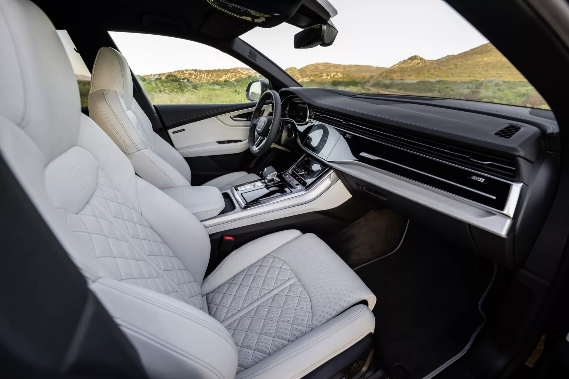 Interiér Audi Q8 2023 (4M-Facelift) s bielymi prešívanými koženými sedadlami, luxusným dizajnom stredovej konzoly, rozsiahlym dotykovým informačno-zábavným systémom a modernými ergonomickými prvkami, zhotovené z pohľadu spolujazdca