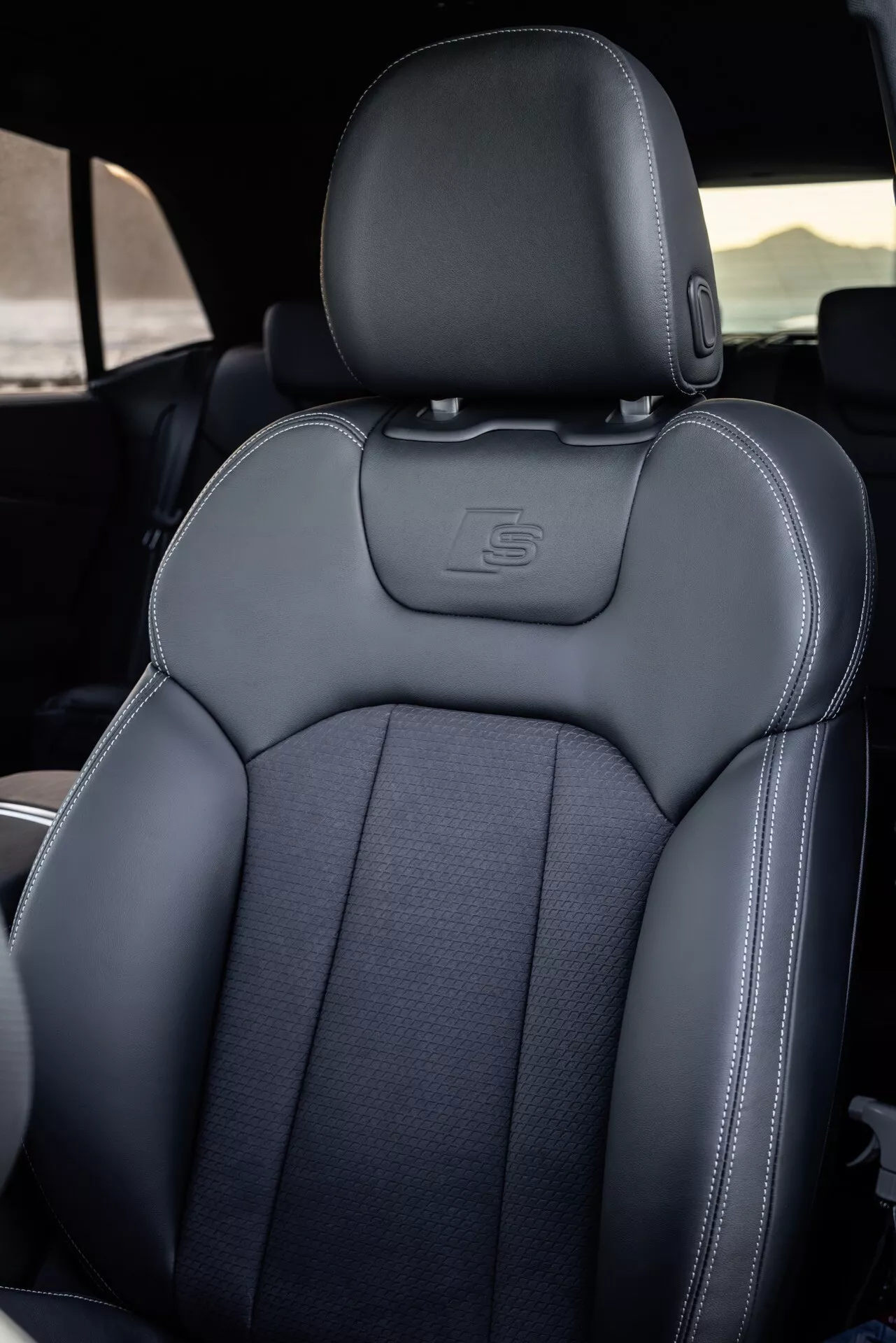 Interiér Audi Q8 (4M-Facelift) 2023 so zameraním na sedadlo vodiča s detailným prešívaním, luxusnými materiálmi a športovou ergonómiou, čiastočne viditeľný volant označujúci stranu vodiča
