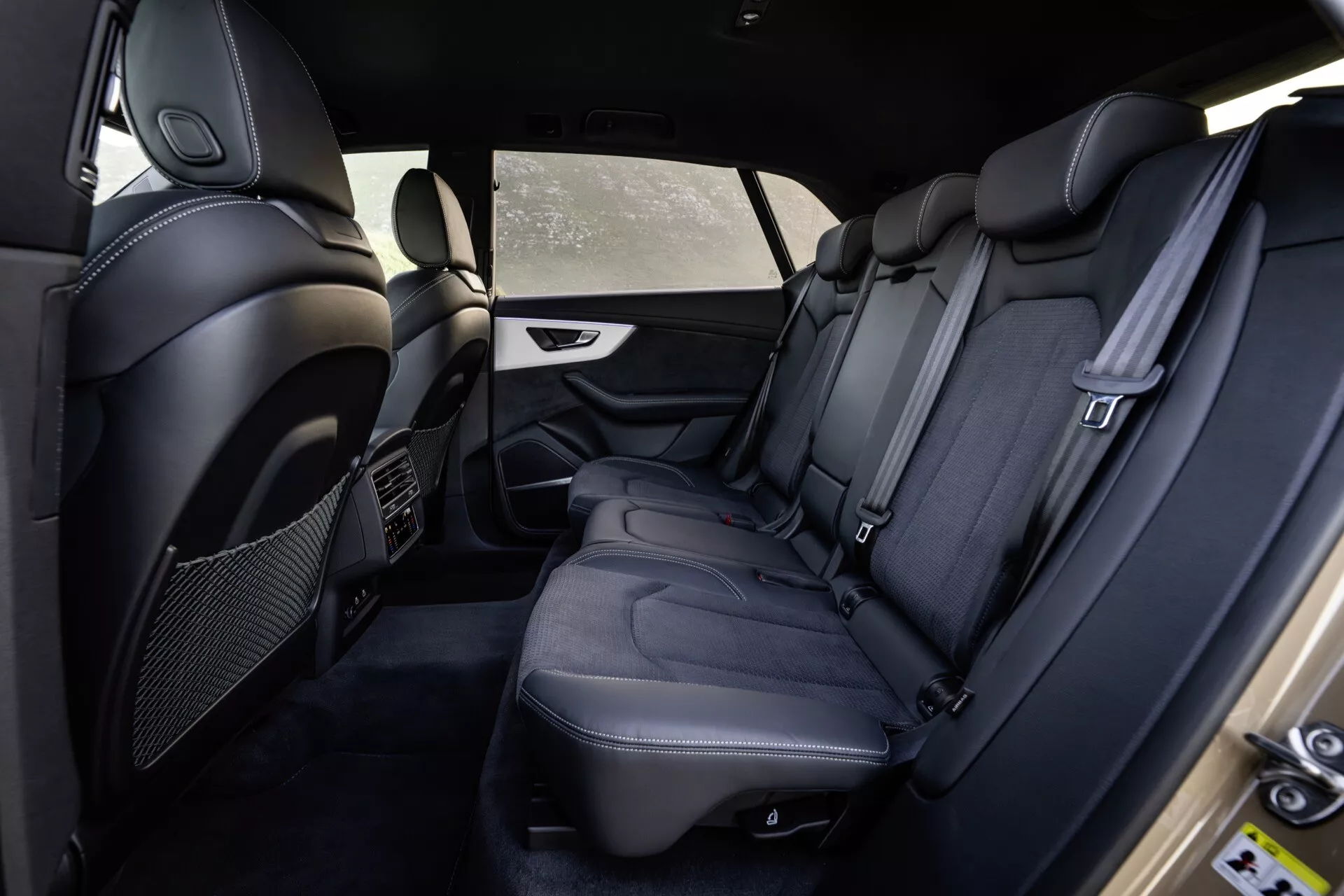 Interiér Audi Q8 4M-Facelift 2023 s pohľadom na zadný cestujúci priestor zo strany vodiča, prémiové čierne kožené sedadlá, detailné prešívanie, luxusné vybavenie a bezpečnostné prvky