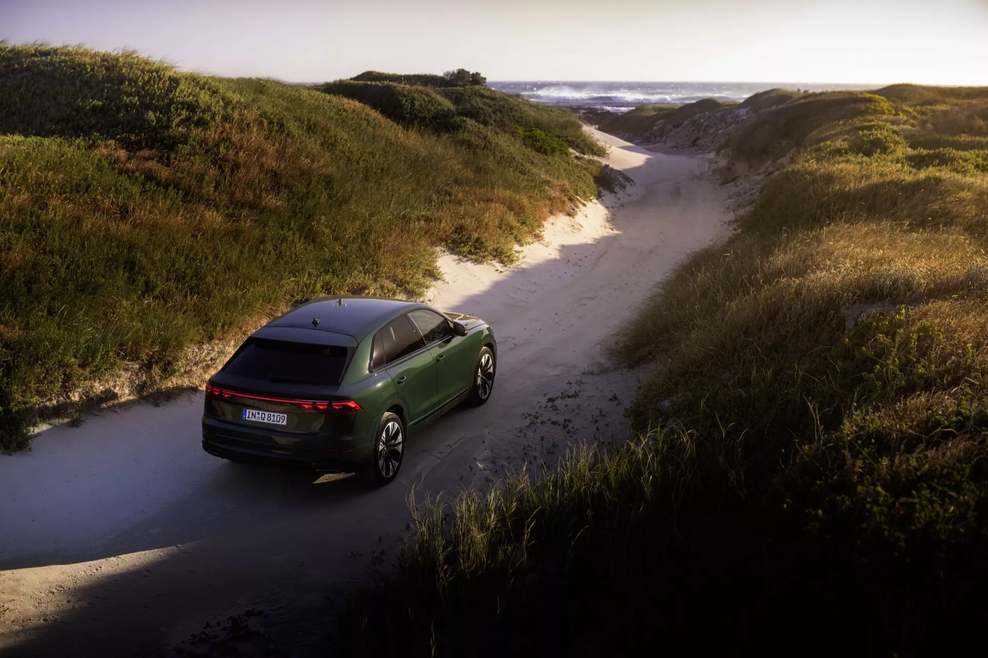 Audi Q8 2023 (4M-Facelift) zachytené z vtáčej perspektívy predvádzajúce aerodynamický dizajn, LED zadné svetlá a prémiové zliatinové kolesá v prírodnom off-road prostredí
